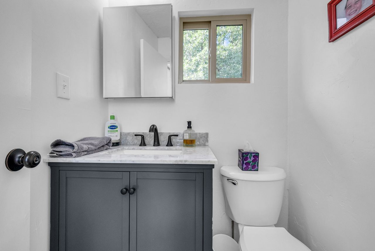 Bathroom vanity with a dark gray cabinet, white countertop, and dark-finished faucet