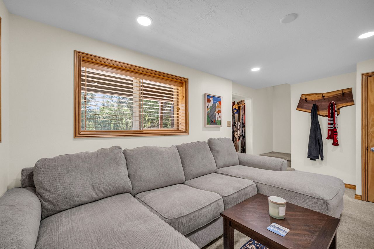 Living space featuring a large window with wood trim and horizontal blinds, recessed lighting, and light-toned walls