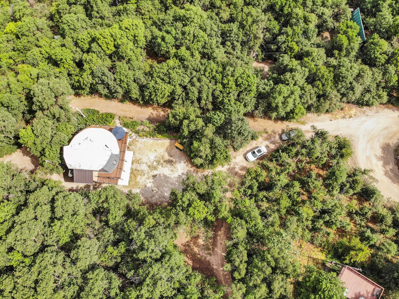 Circular roof structure surrounded by abundant natural greenery