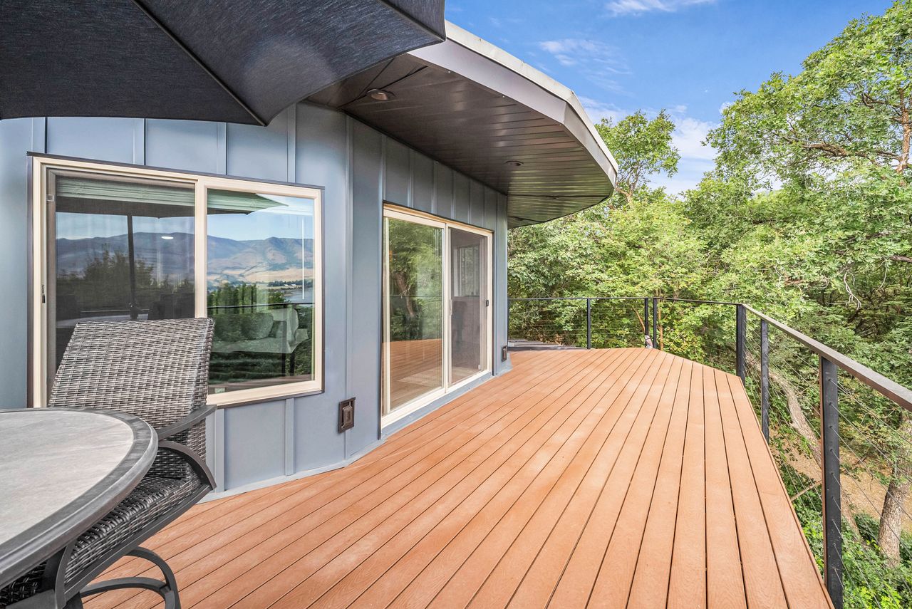 Expansive outdoor deck featuring wood-finish flooring, a contemporary cable railing system, and direct access to interior spaces through sliding glass doors