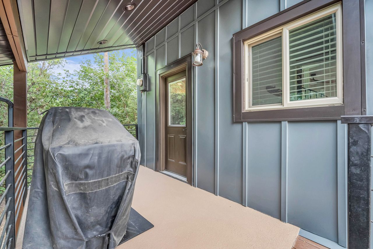 Outdoor patio featuring durable board and batten siding, a glass-panel door, and a sliding window with blinds