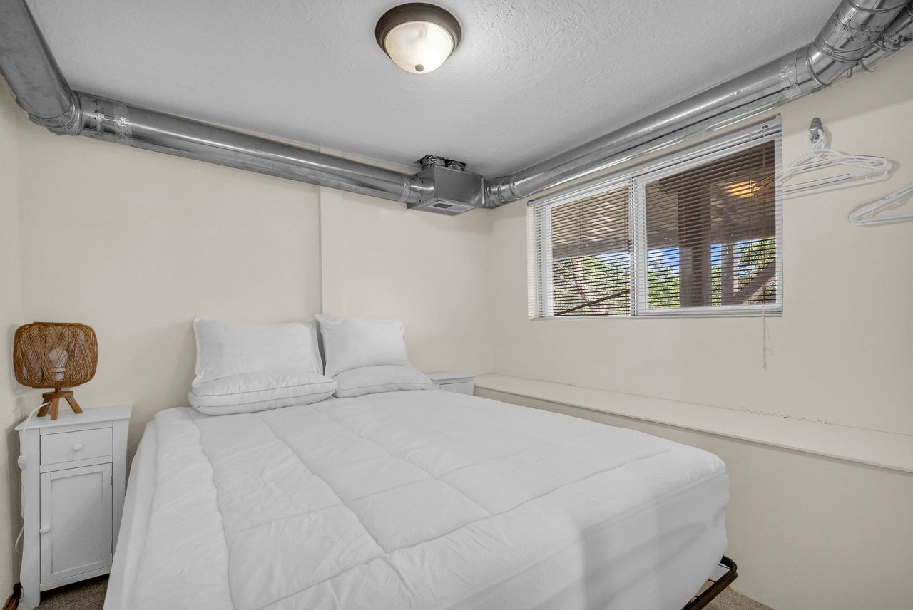 Bedroom with a window featuring horizontal blinds, a ceiling-mounted light fixture, and visible ceiling ductwork