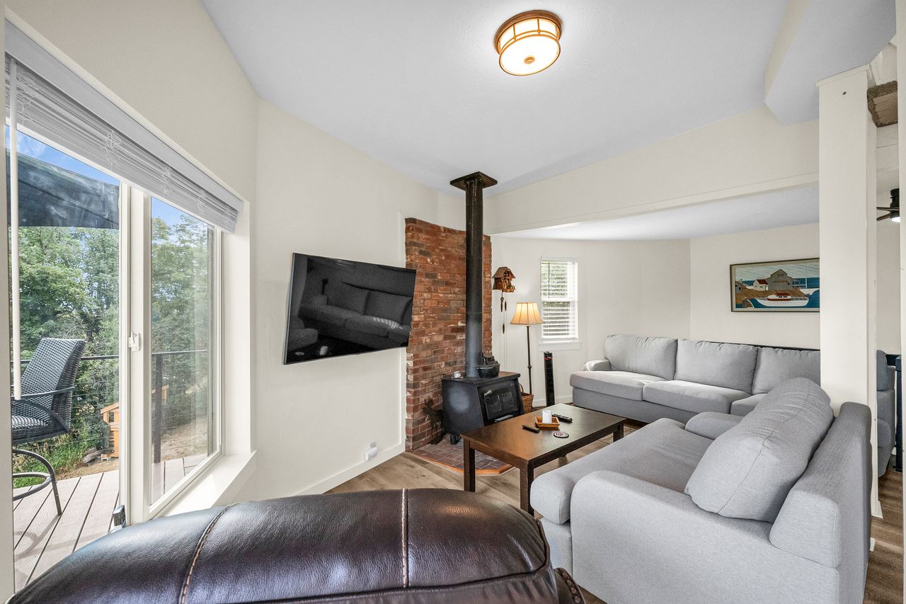 Living area featuring wood-finish flooring and a wood-burning stove with a brick backdrop