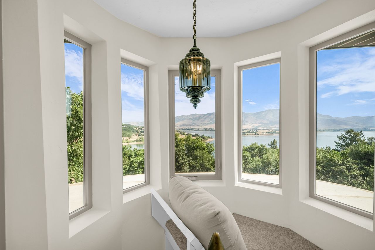 Bay window featuring multiple large windows, a decorative pendant light fixture, and carpeting