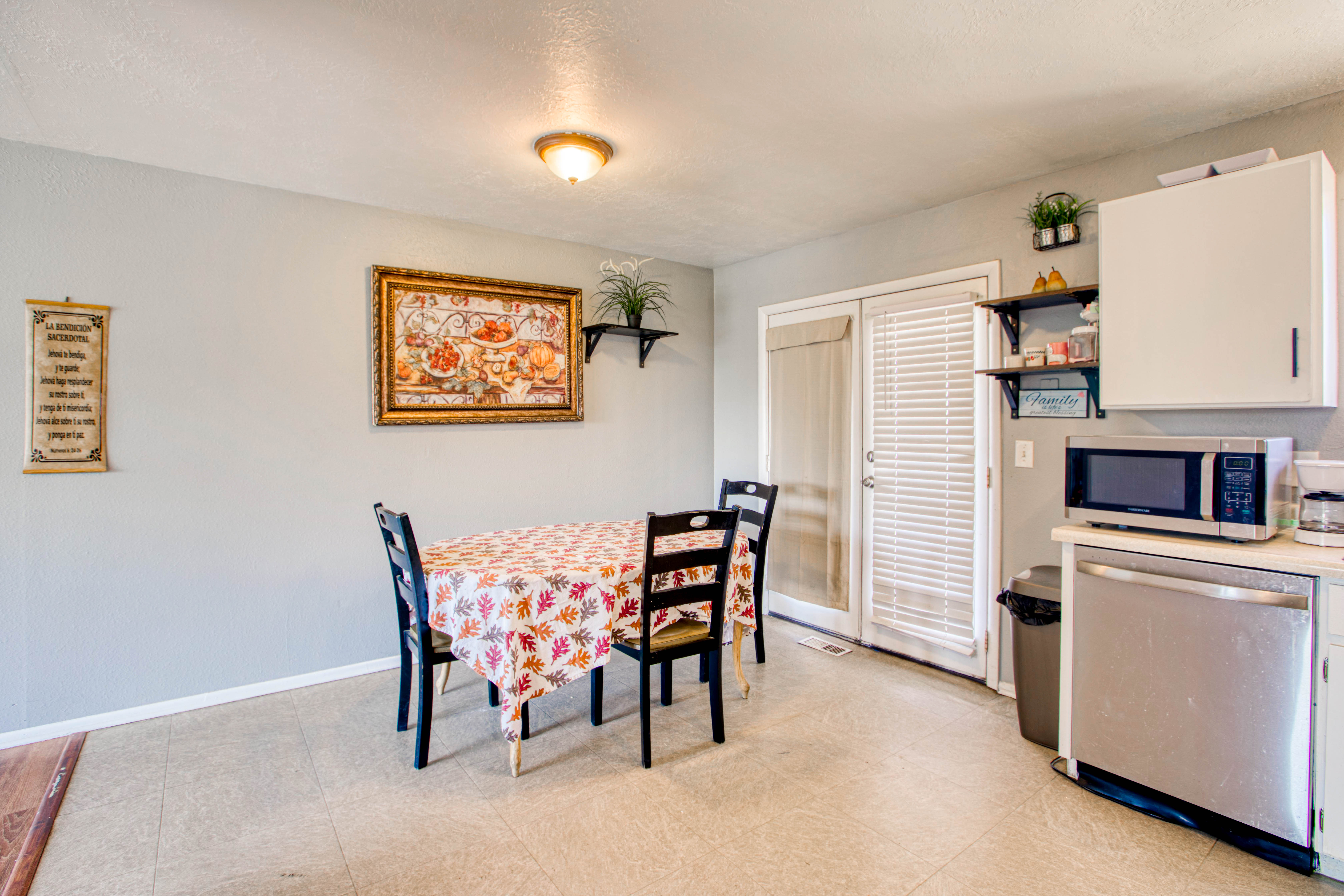 Eat-in kitchen featuring light gray walls, built-in white cabinetry, stainless steel appliances, and a double patio door