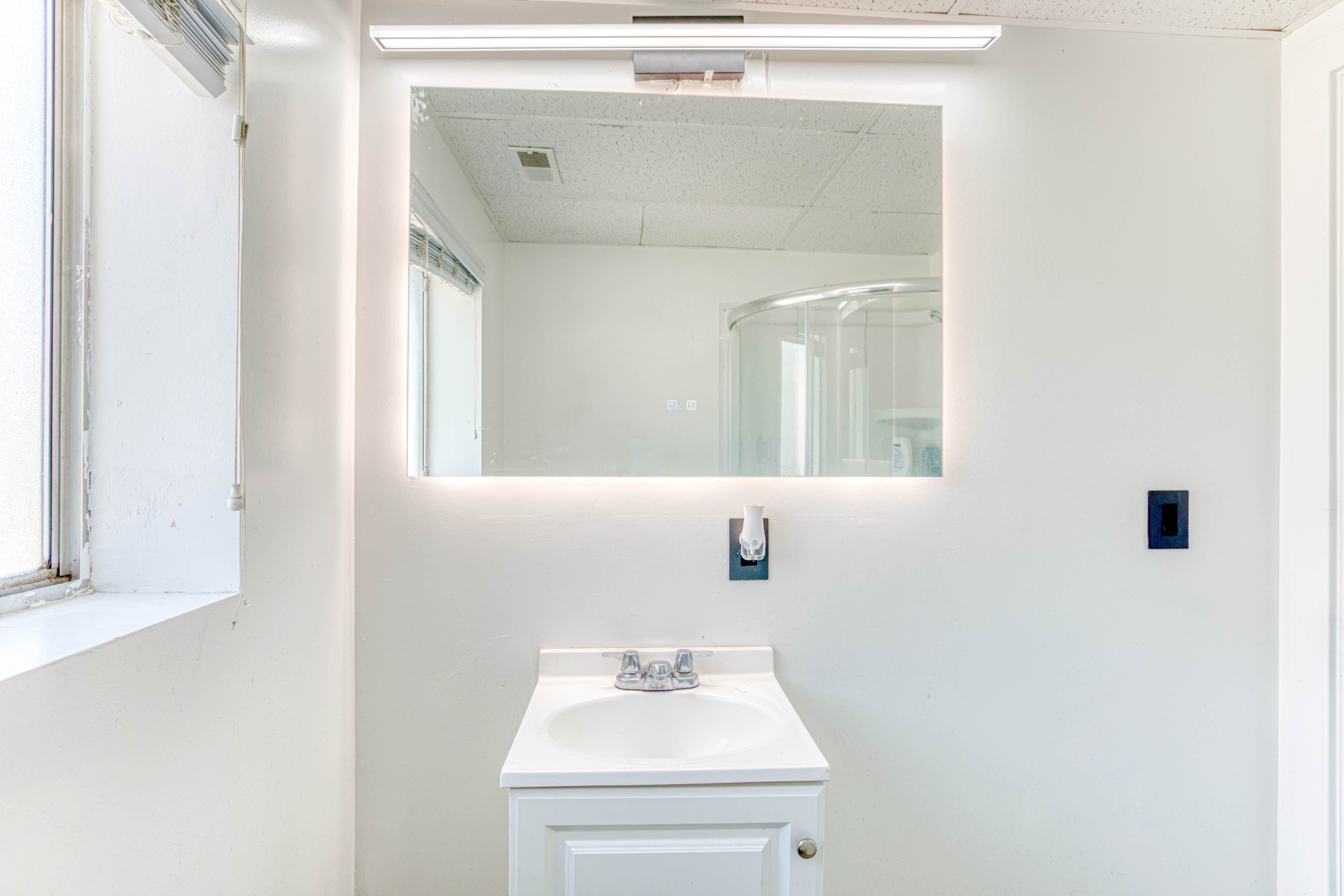 Bathroom vanity featuring a single basin sink, white cabinetry, and a countertop