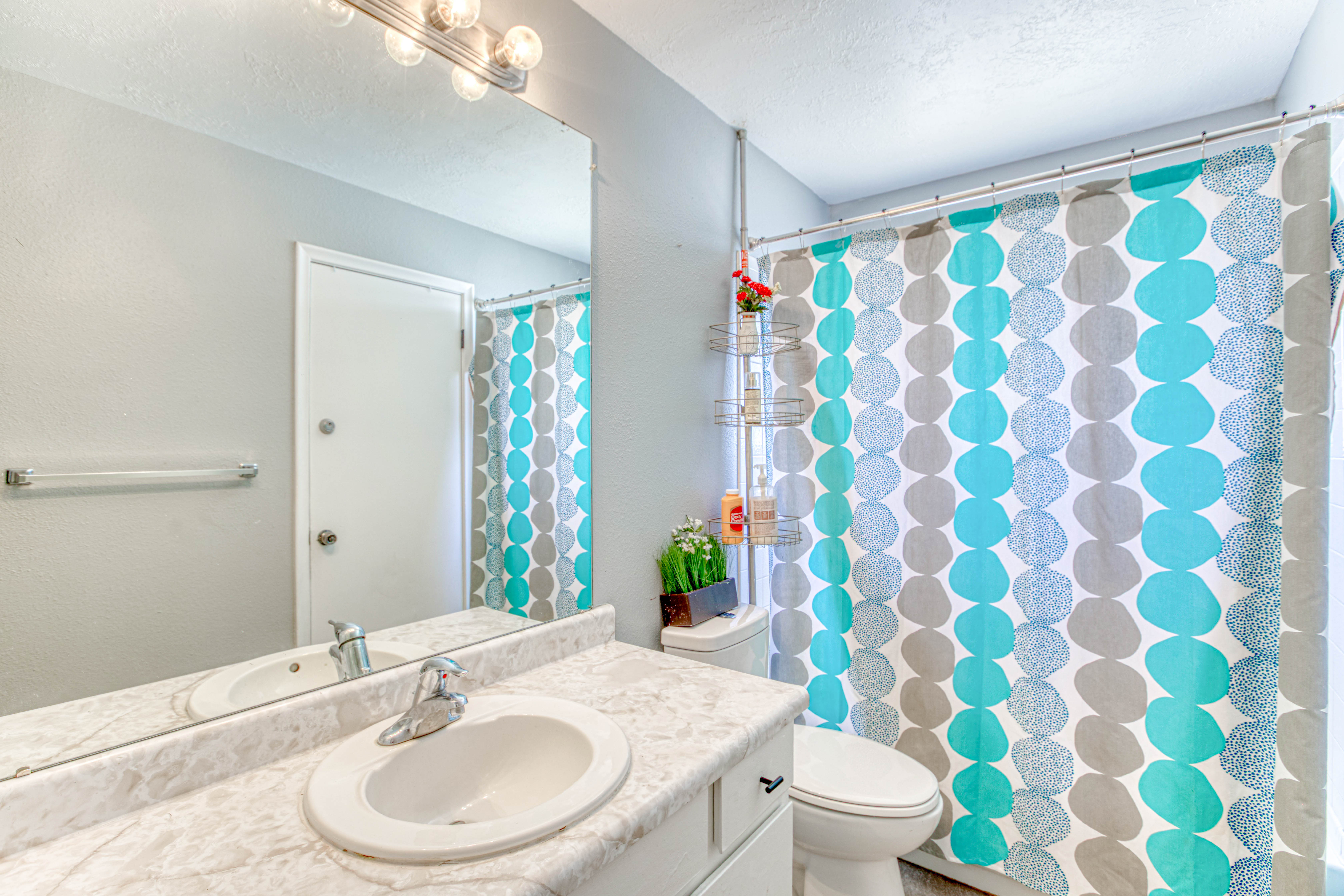 Bathroom featuring a single vanity with an integrated sink, a large wall-mounted mirror, and a multi-bulb vanity light fixture