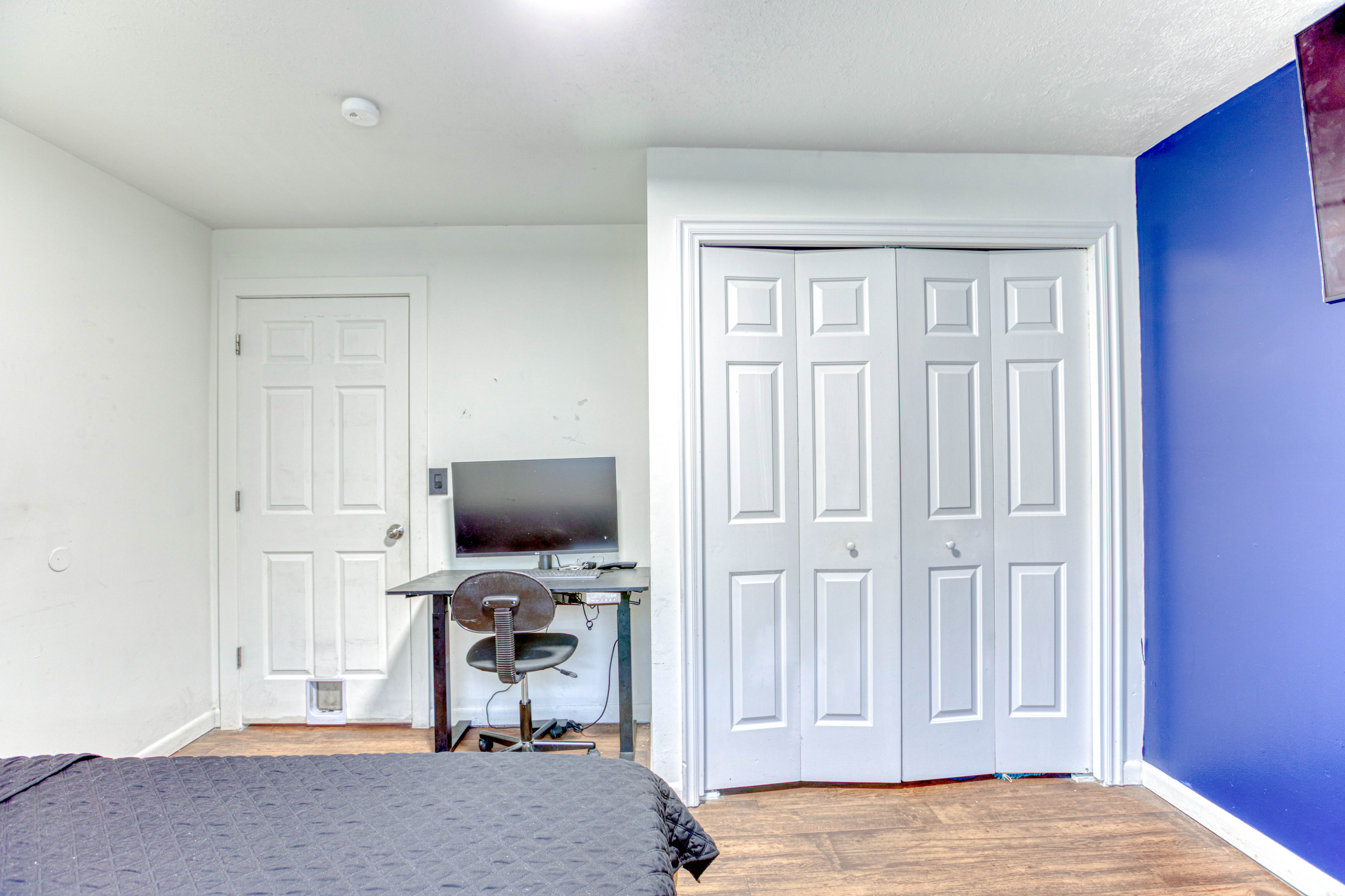 Room featuring wood-finish flooring, a white paneled door, and bi-fold closet doors