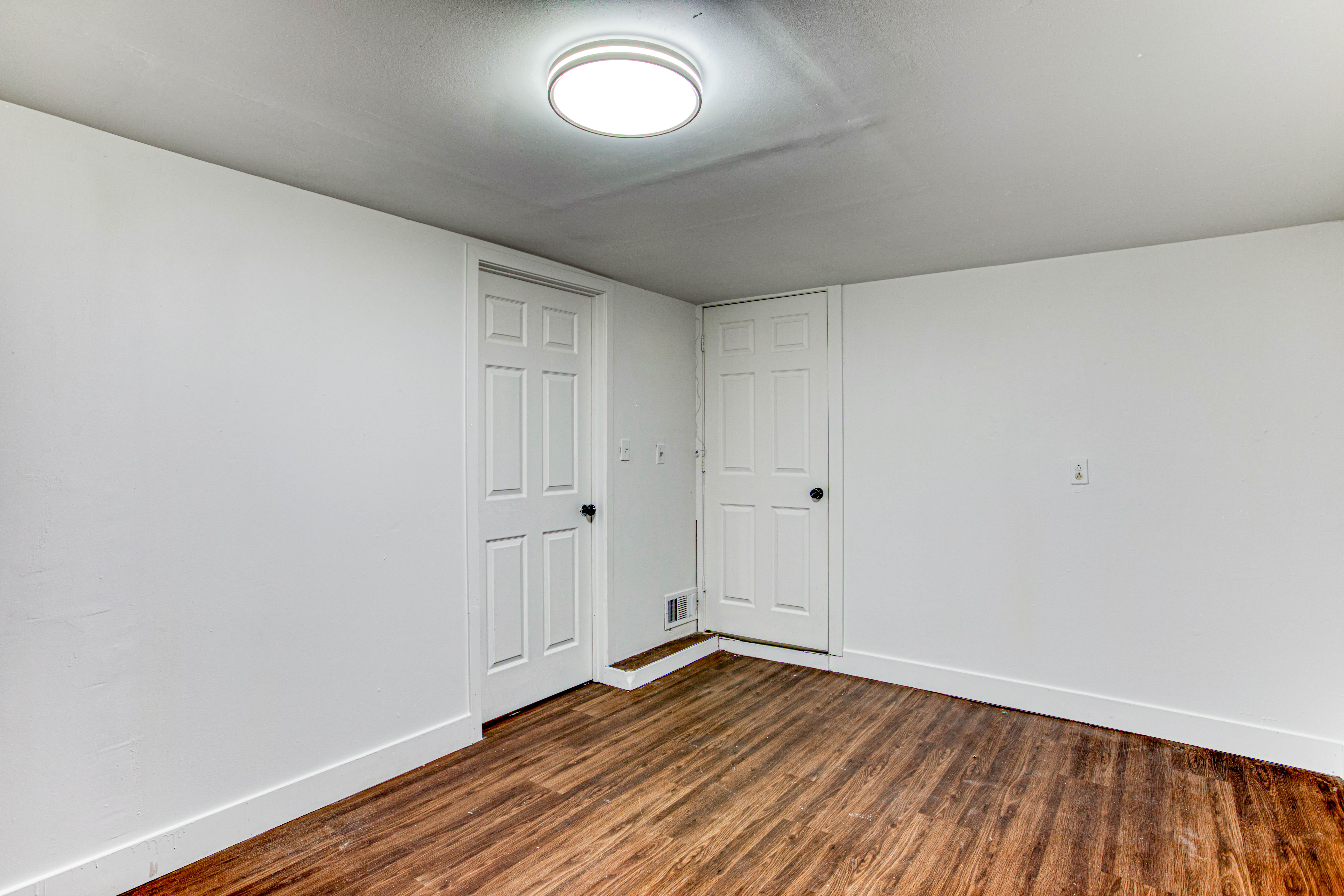 Room featuring wood-finish flooring, white walls, and bright overhead lighting