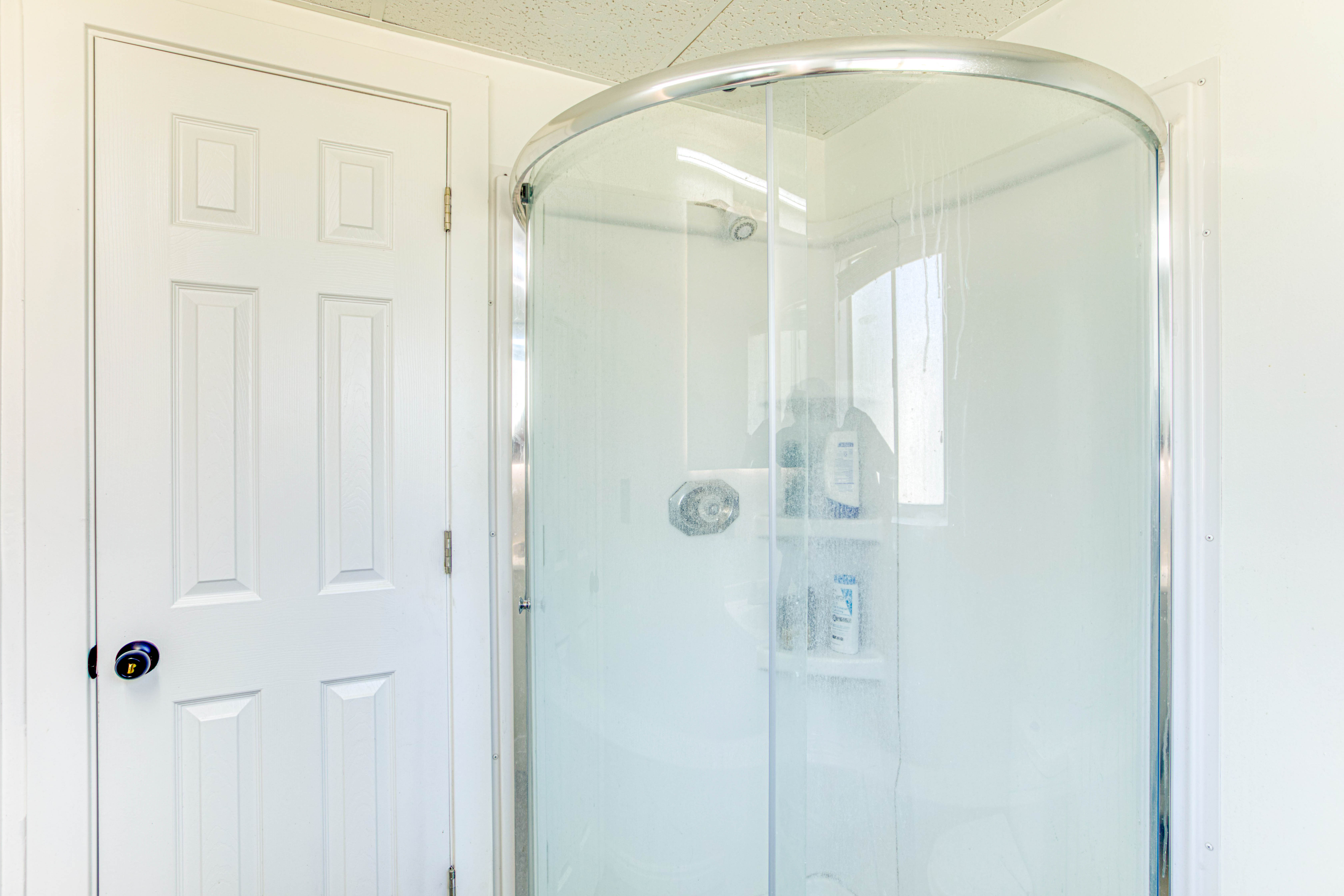 Curved glass shower enclosure with chrome-finish hardware and integrated shelving