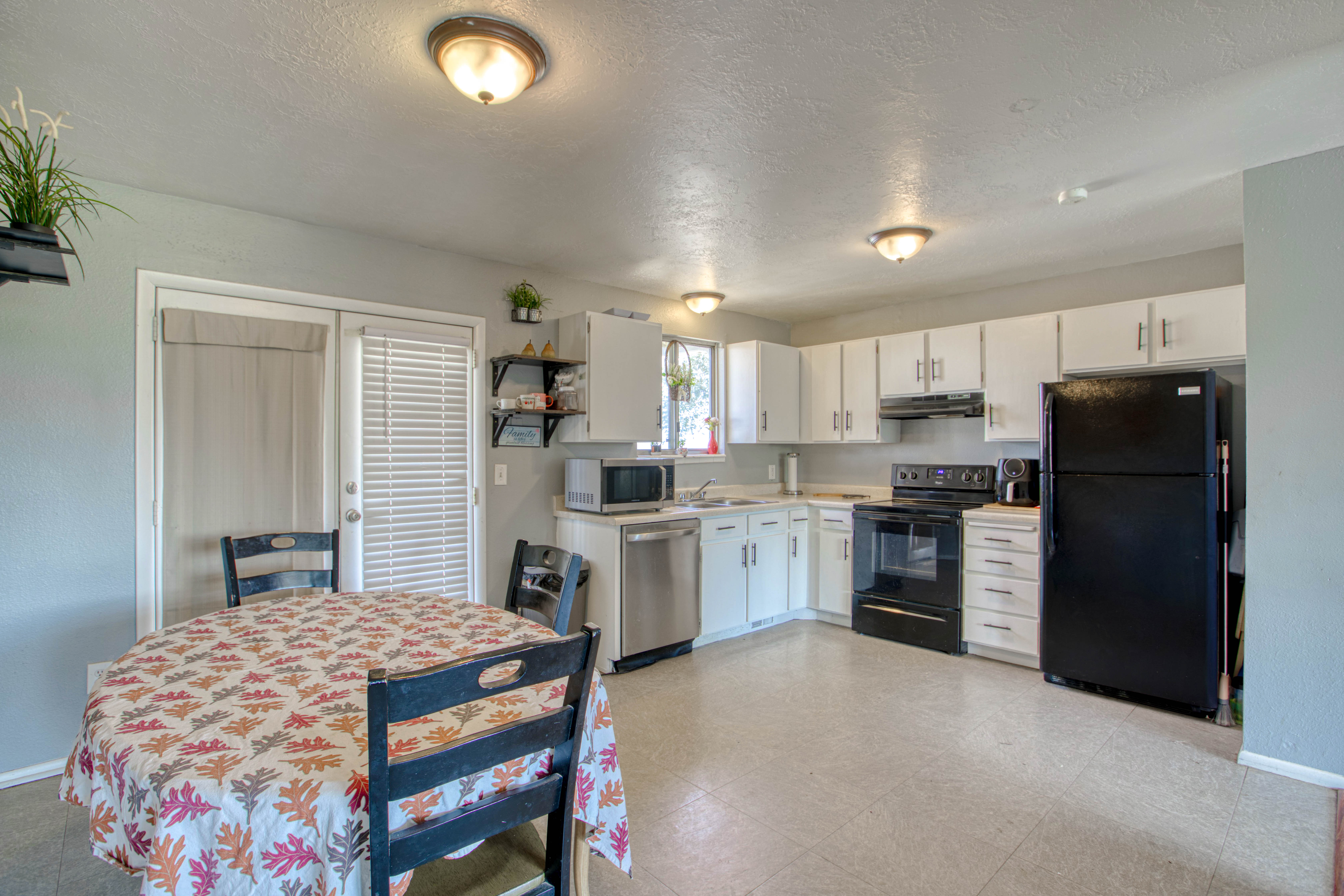 Kitchen featuring white cabinetry, black appliances, light-toned flooring, and a glass-paneled patio door