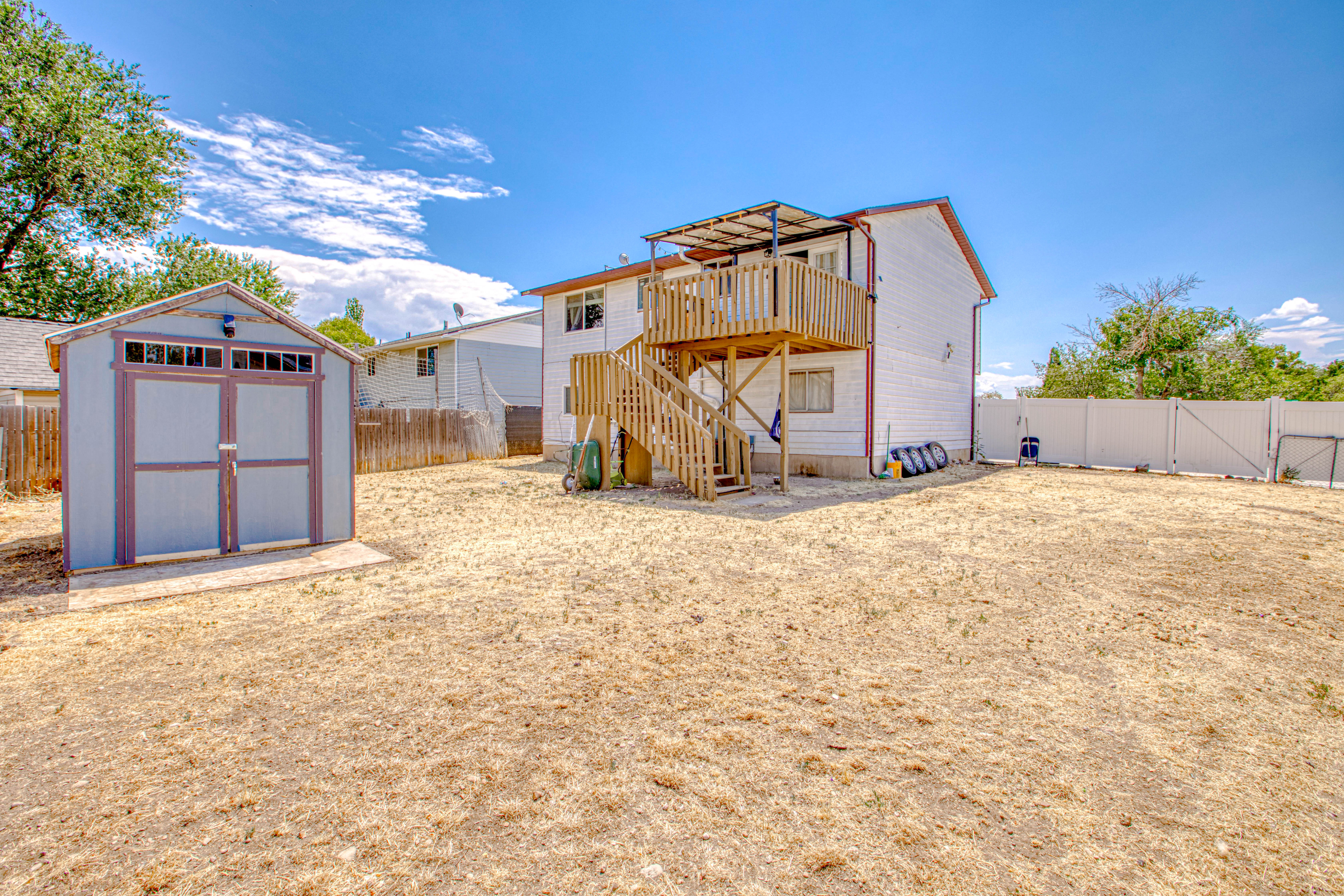 Spacious backyard featuring a two-story residence with an elevated wood deck and staircase