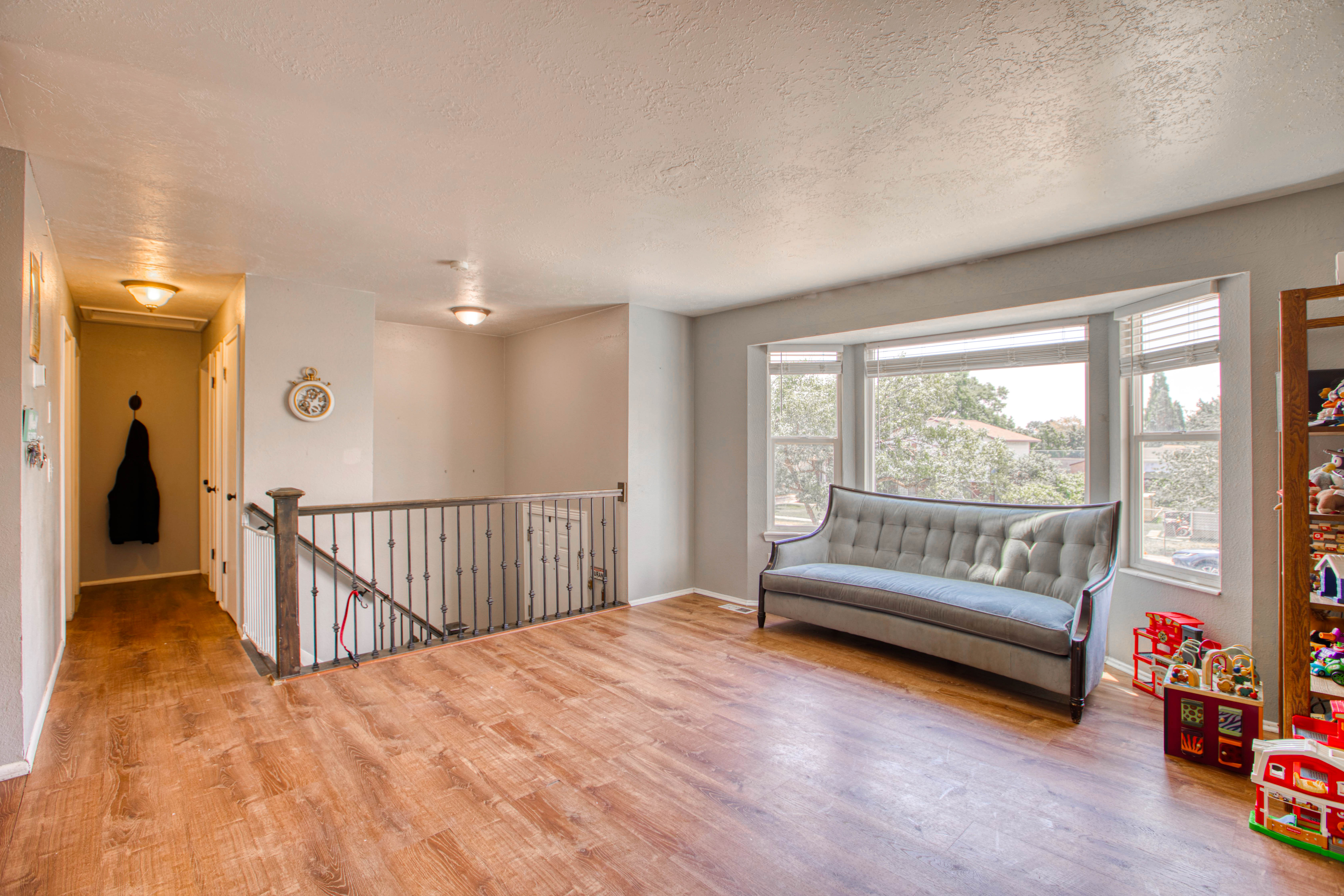 Bright interior space featuring wood-finish flooring and a bay window with blinds