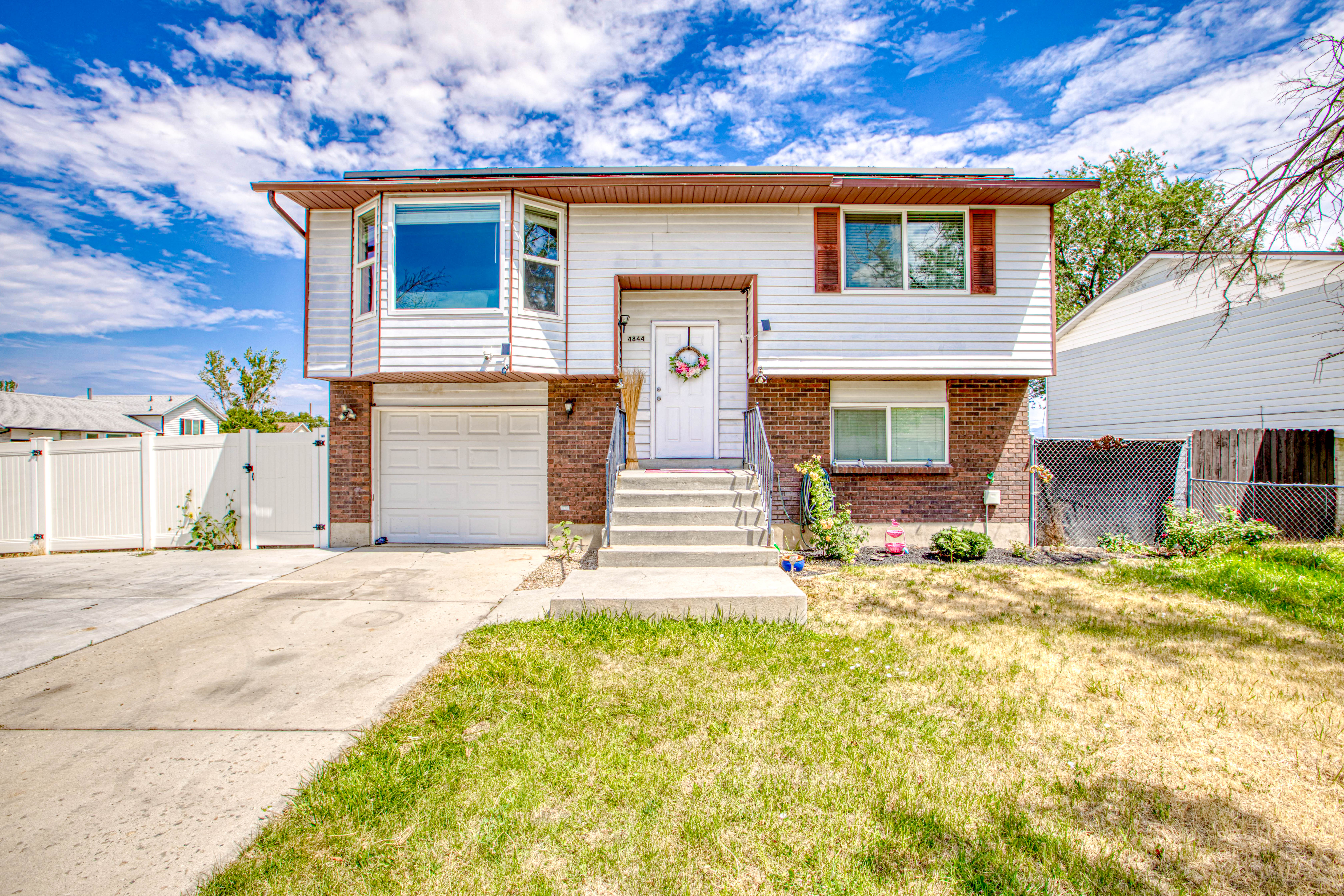 Split-level residence featuring a brick and siding exterior, concrete driveway, attached garage, and a bay window on the upper level