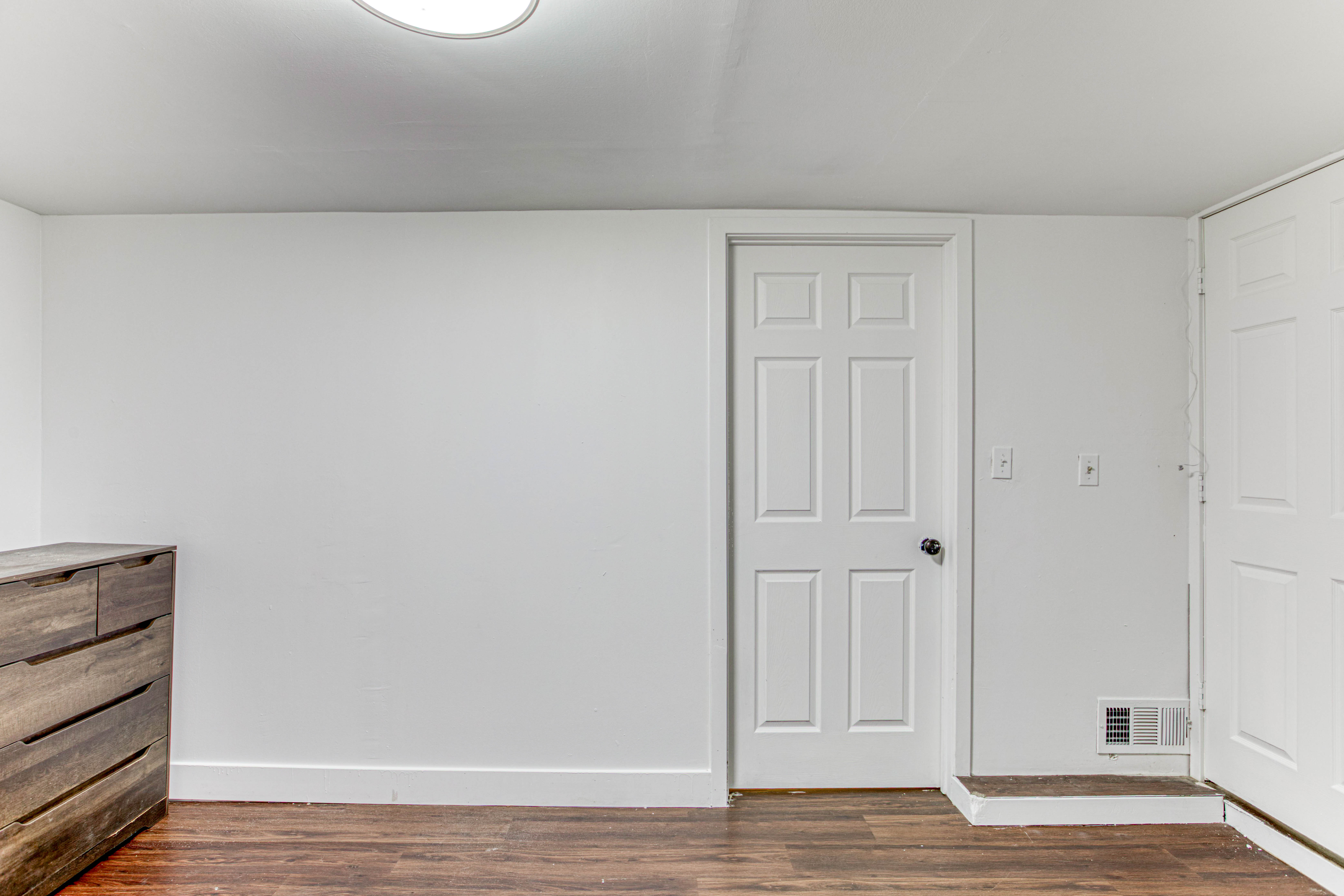 Room featuring wood-finish flooring, white baseboards, a flat white ceiling, and a flush-mount ceiling light fixture