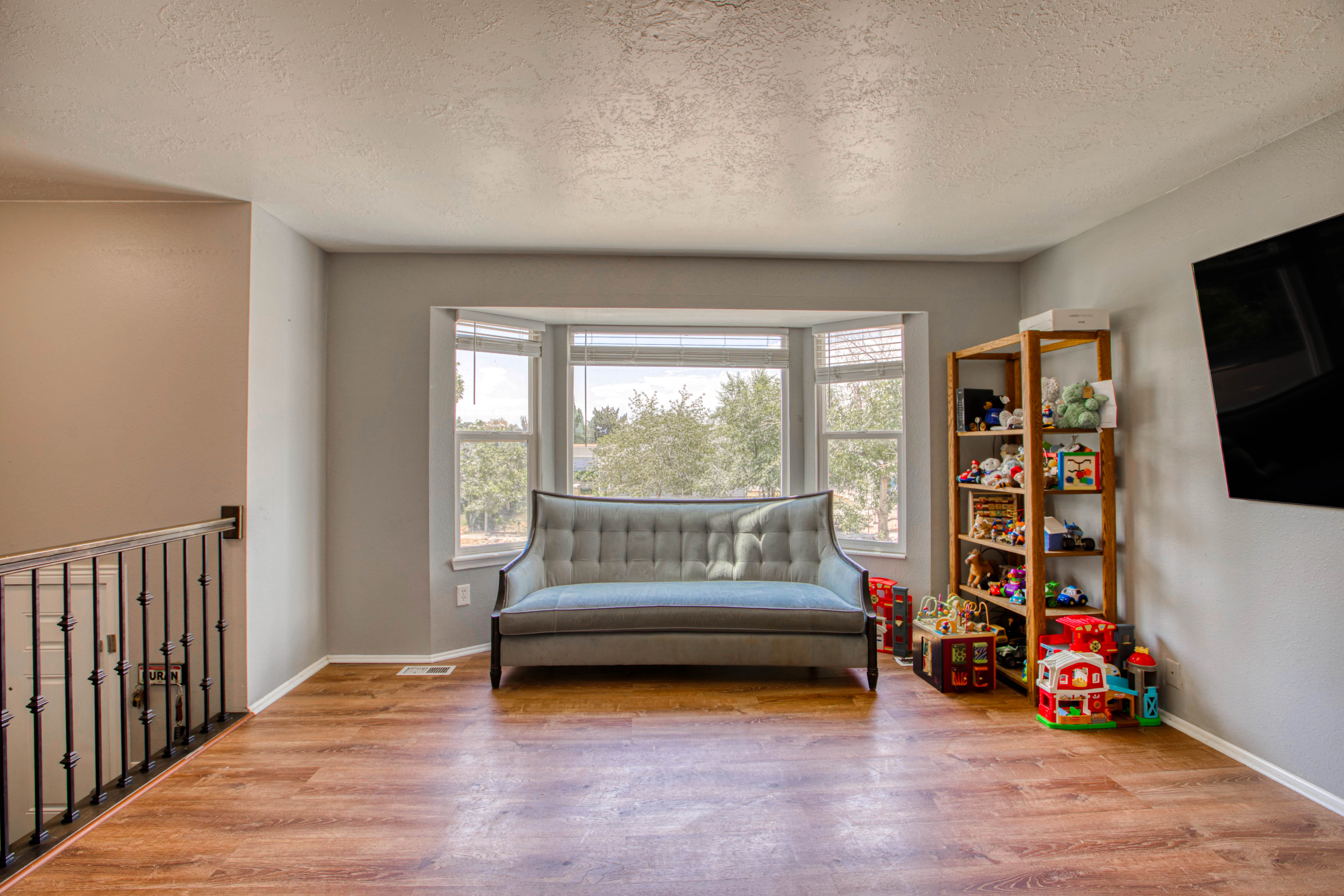 Spacious room featuring a bay window, wood-finish flooring, and light gray wall color