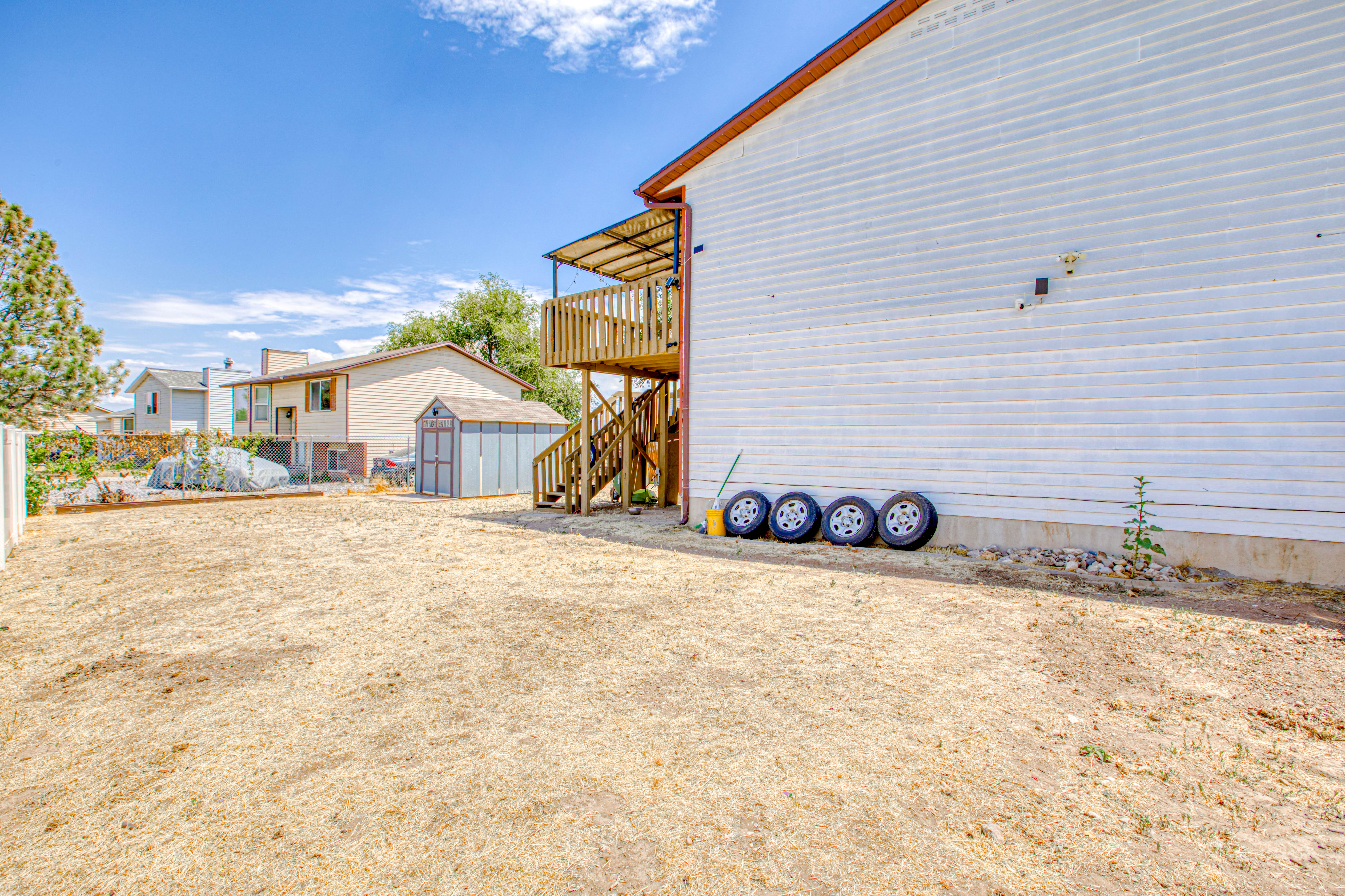 Expansive backyard featuring a wood deck with stairs, a shed, and white vinyl siding on the property