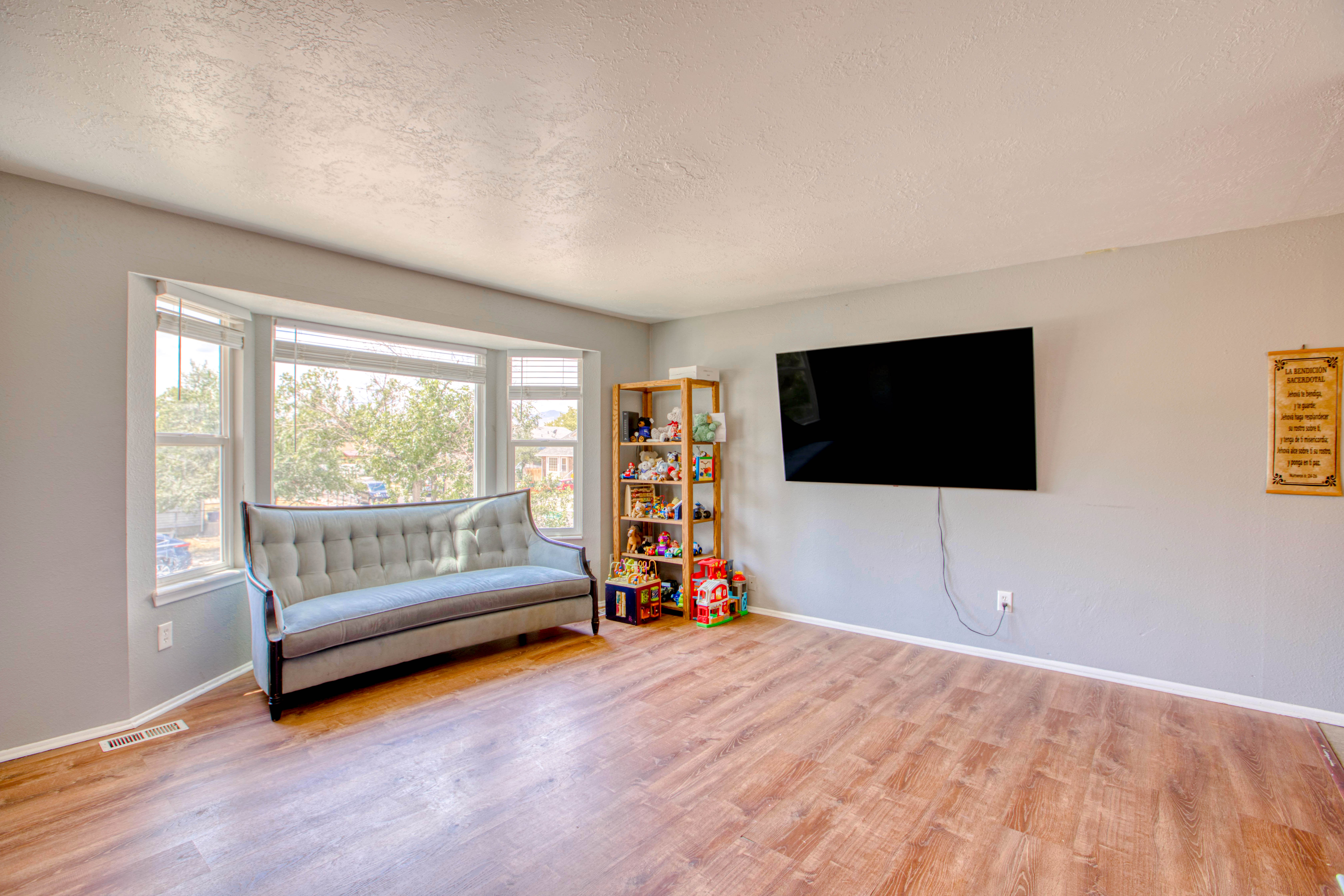 Expansive living area featuring wood-finish flooring, a bay window with multiple panes, and light gray painted walls