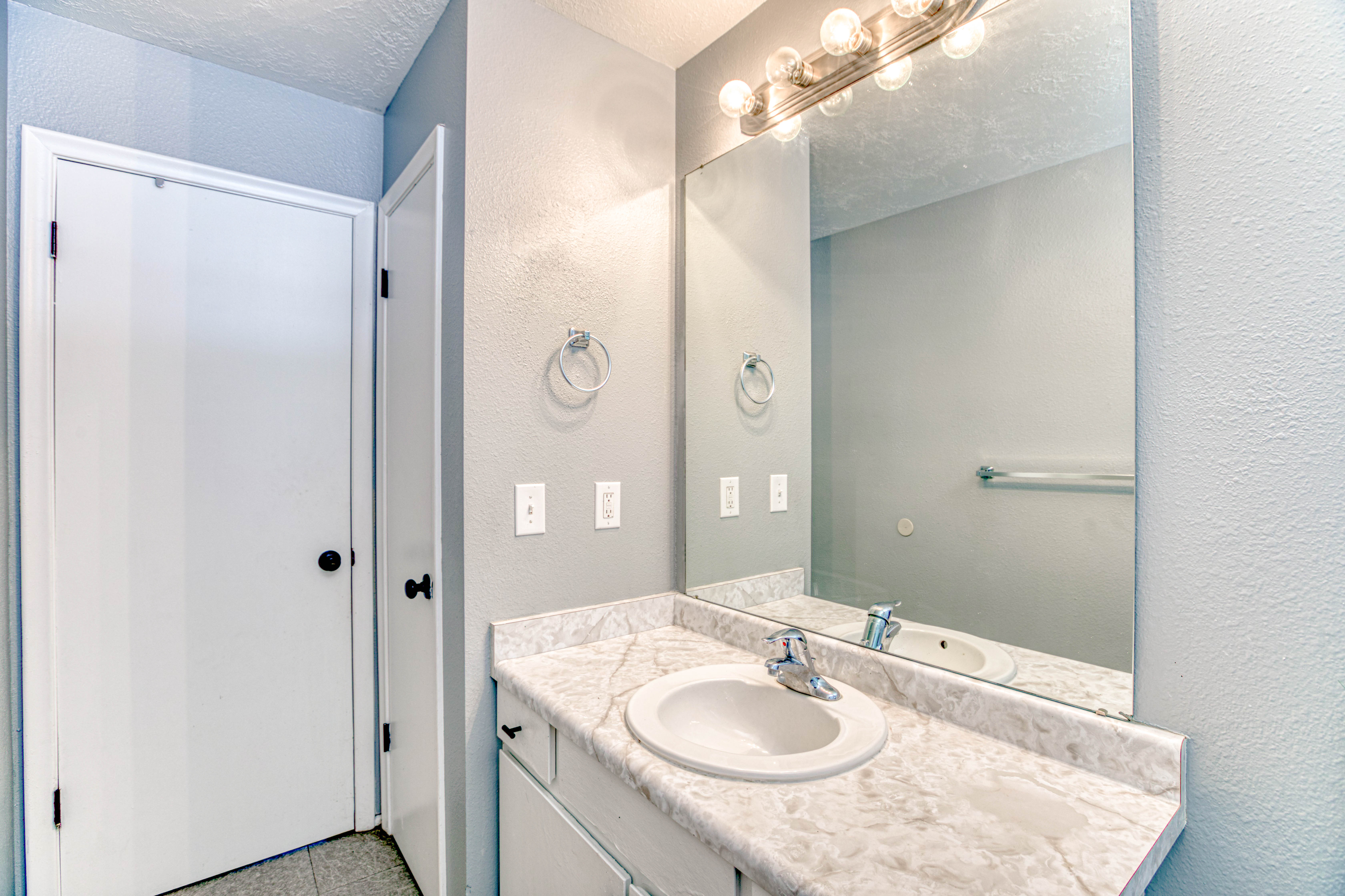 Vanity with a white, integrated sink and a stone-finish countertop