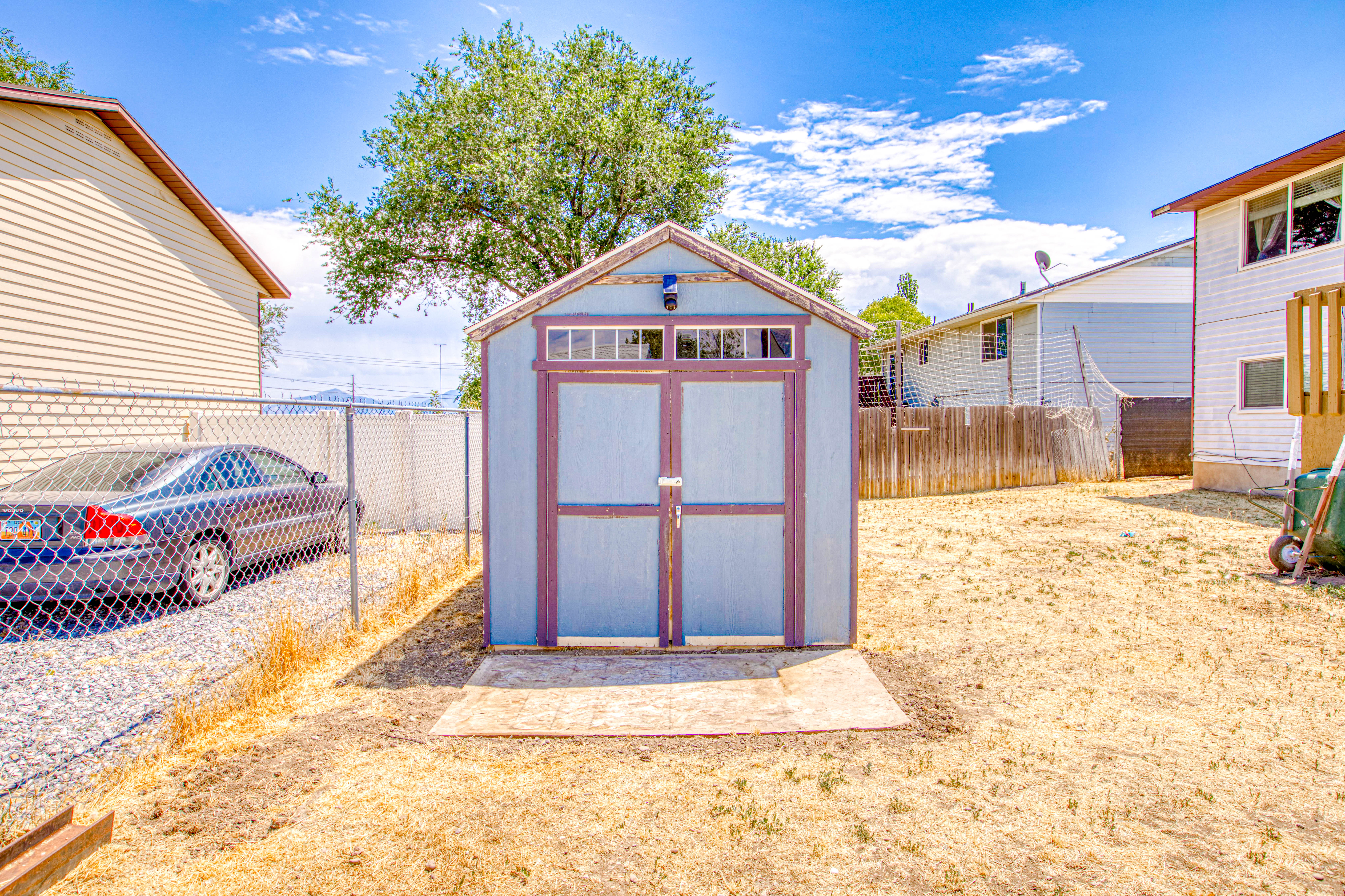 Freestanding storage shed with double entry doors and upper transom windows, set on a concrete pad