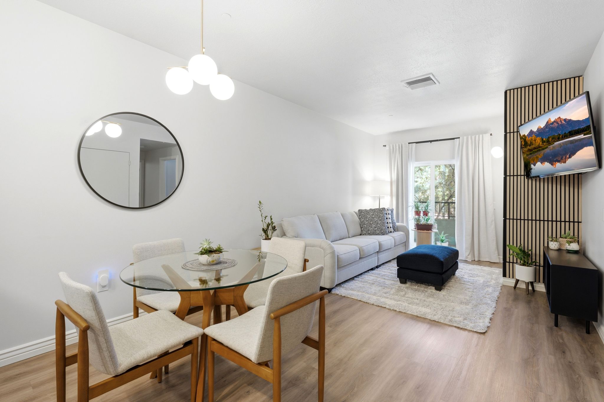 Open-concept living area featuring luxury vinyl flooring.  Room is accented with West Elm chandelier and sconce light fixtures