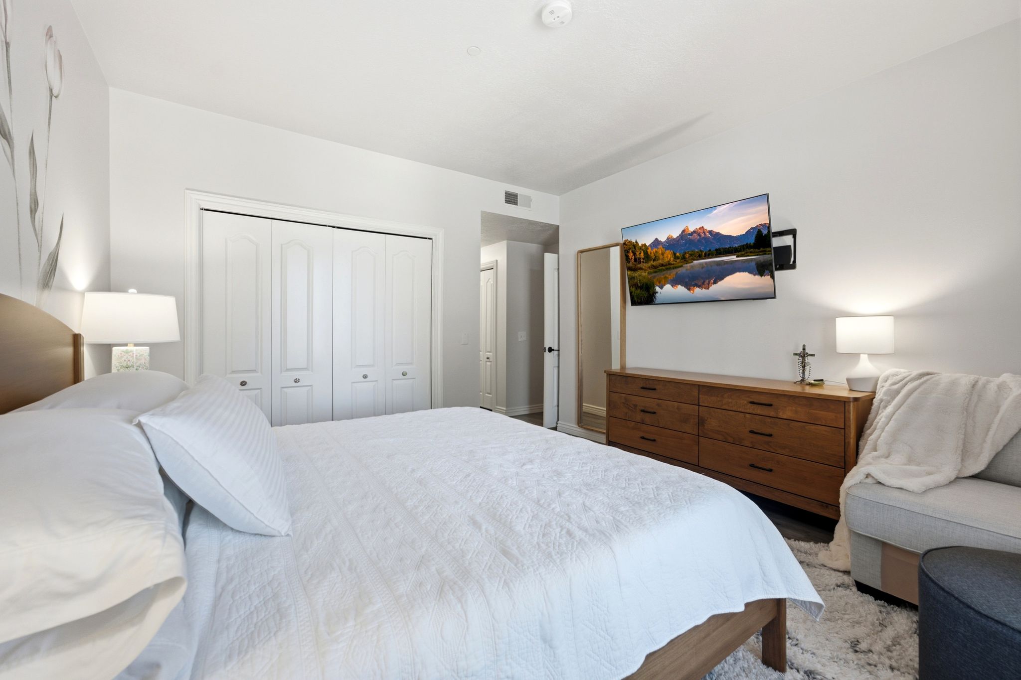 Primary bedroom angle #2.  Wall mount for TV, bi-fold closet doors and access to en suite.