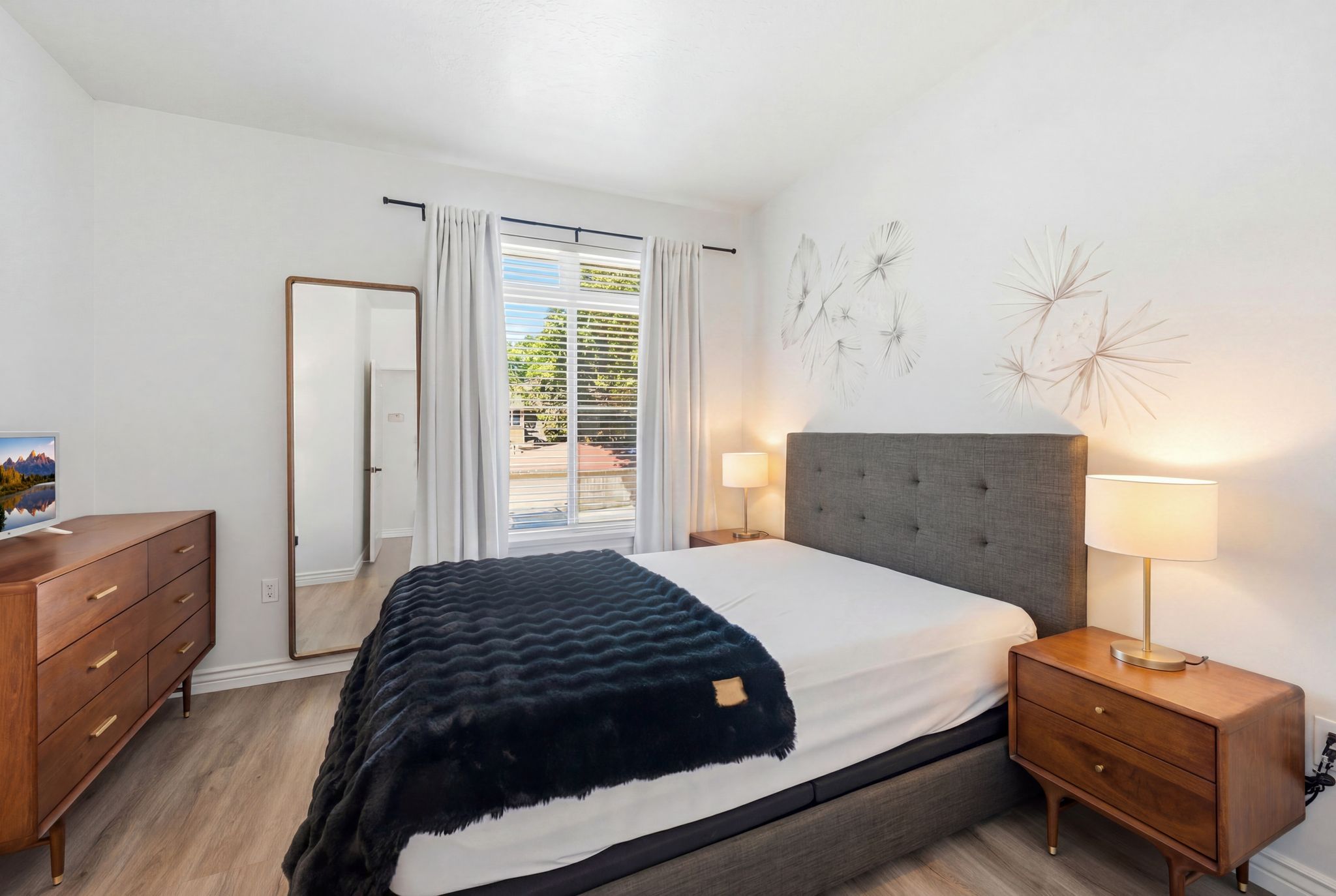 Spacious bedroom featuring luxury vinyl flooring, natural light and decorative wall art.
