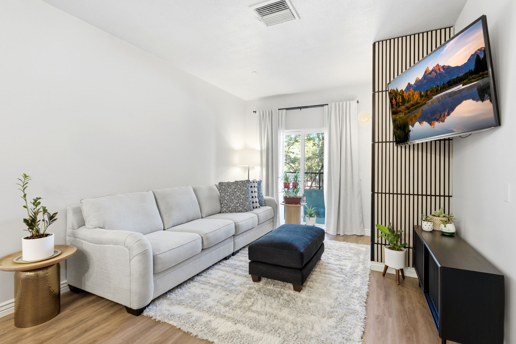 Living area featuring wood-tone luxury vinyl flooring, accent wall, and a sliding door leading to your private balcony