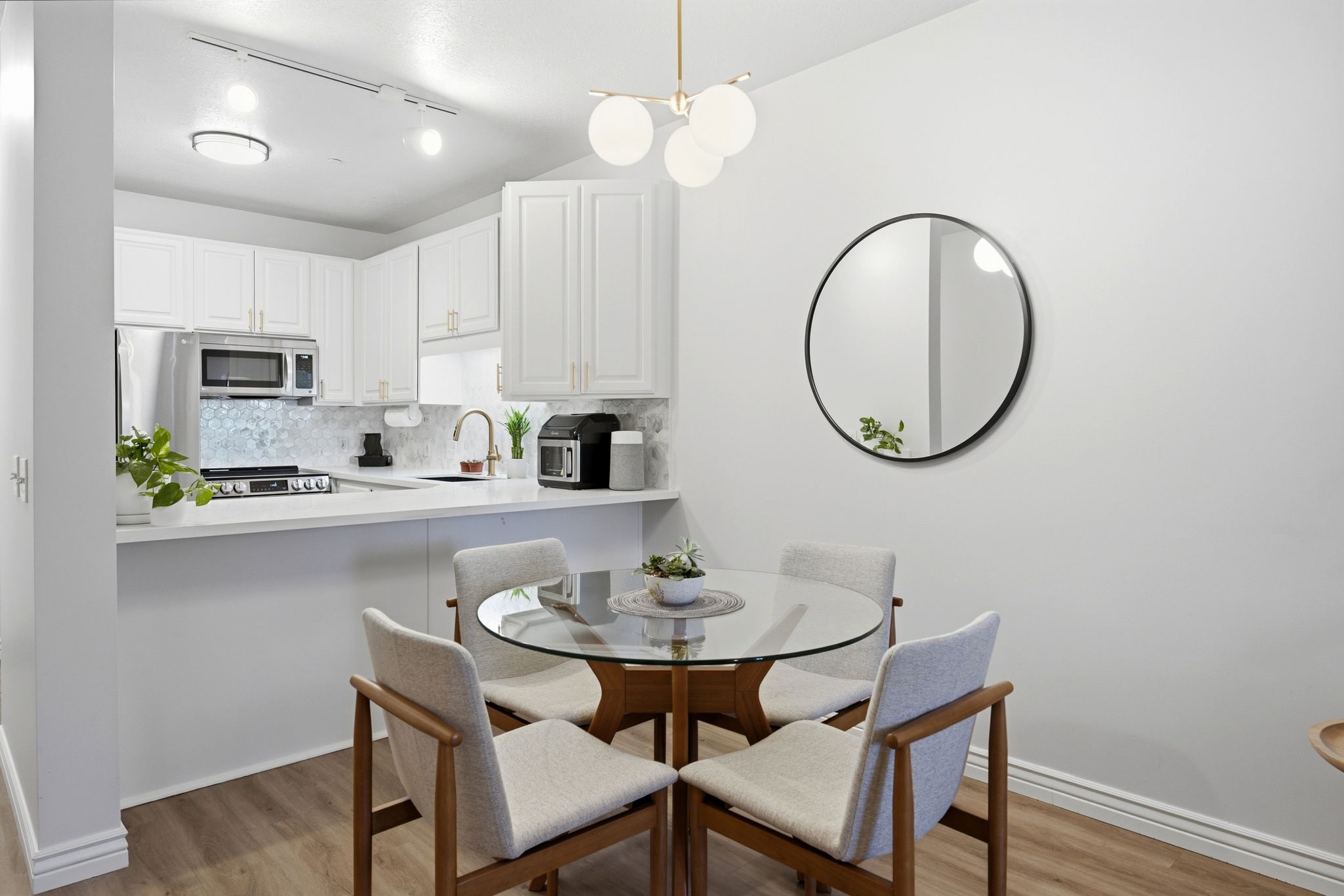 Open-concept dining area featuring luxury vinyl flooring, West Elm chandelier, and a breakfast bar