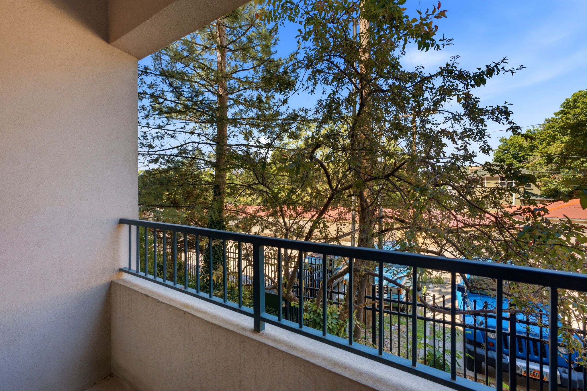 Private balcony off living room featuring a metal railing and stucco exterior