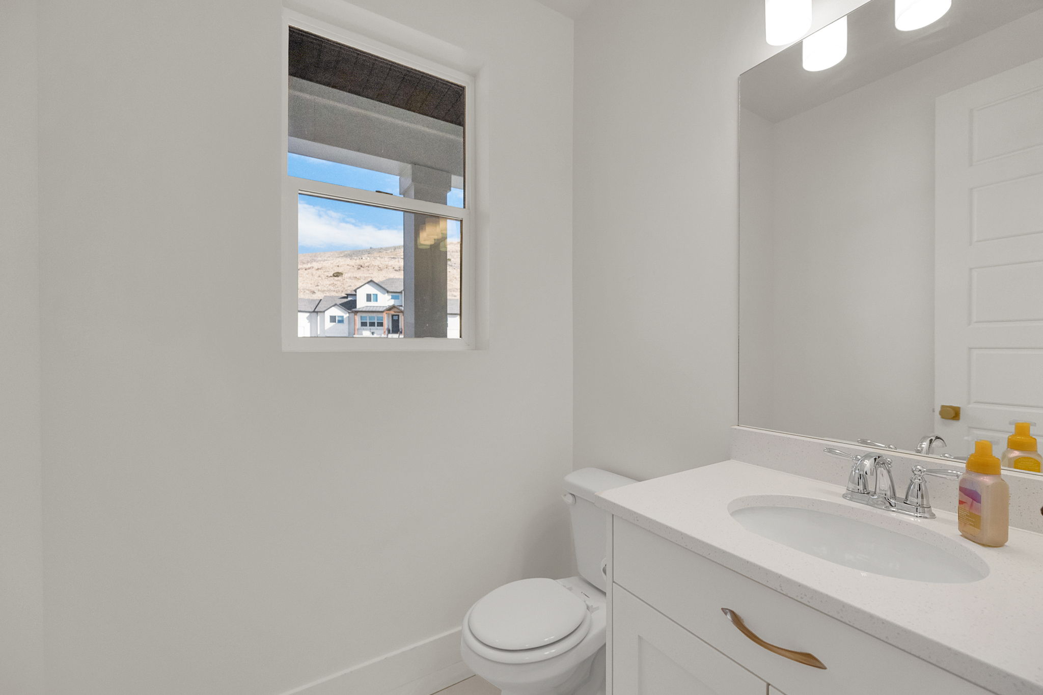 White vanity with an integrated sink, polished chrome faucet, and gold-finish hardware