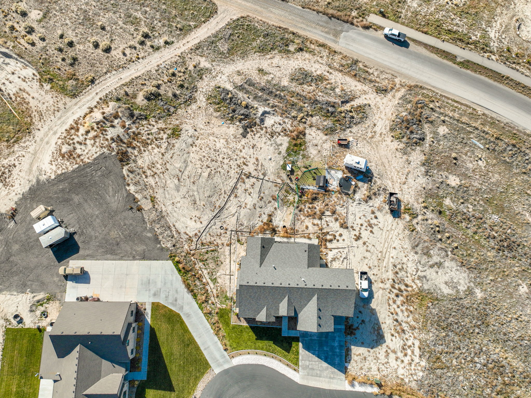 Aerial perspective showcasing a property with a dark grey shingle roof and light concrete driveway