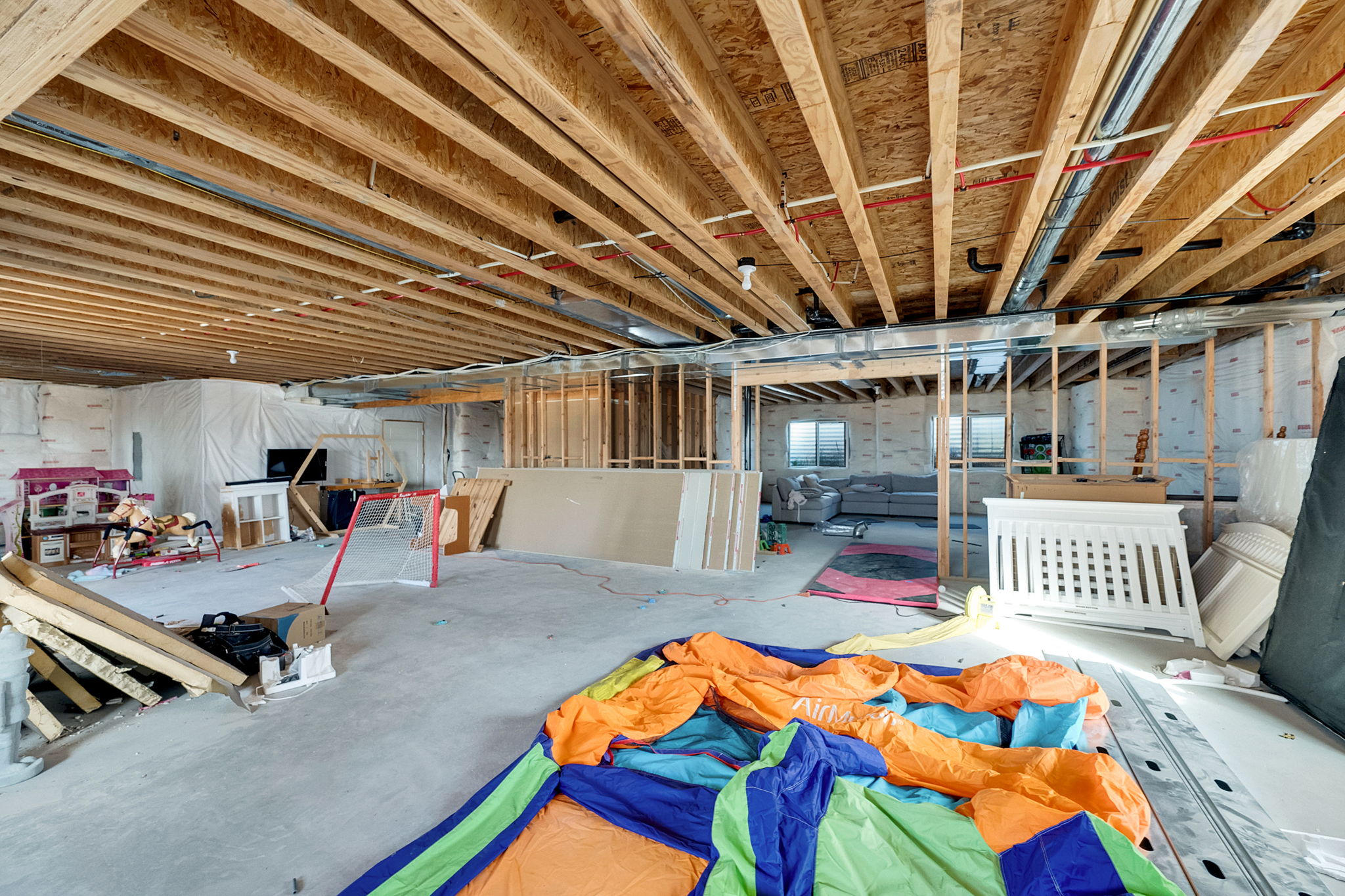 Spacious unfinished lower level featuring exposed wood joists and concrete flooring, ready for customization