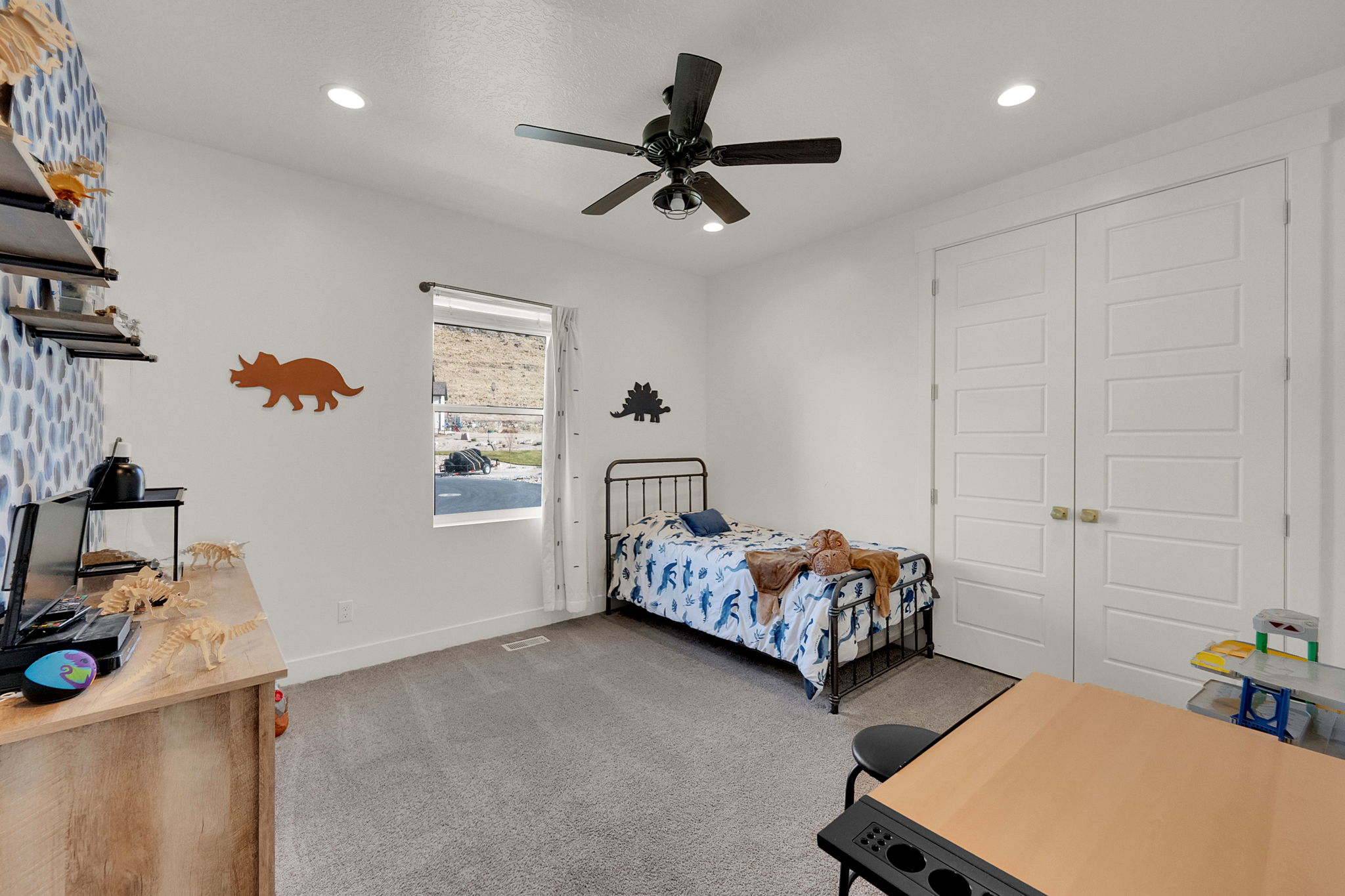 Recessed lighting, a ceiling fan, and plush gray carpeting characterize this bedroom