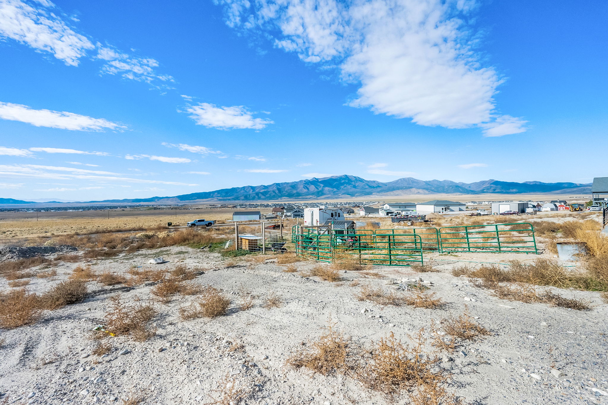 Expansive open land featuring distant mountain ranges and a clear blue sky