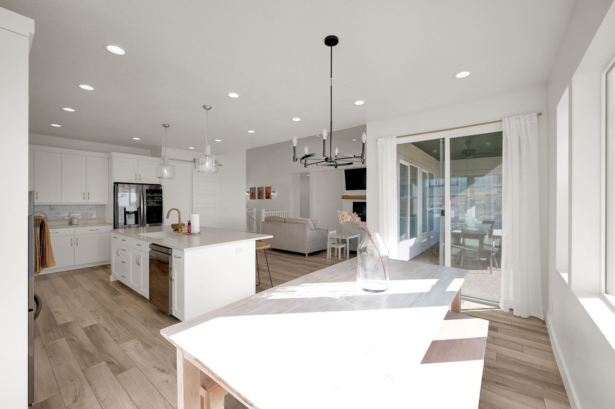 Bright kitchen featuring white cabinetry, a large center island with seating, stainless steel appliances, and wood-finish flooring