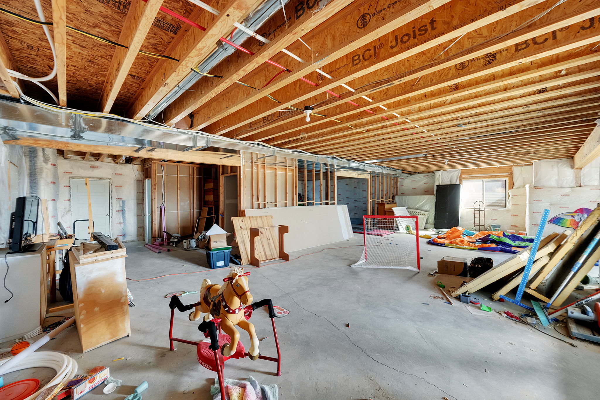 Unfinished basement featuring exposed wood joists, concrete flooring, framed interior walls, and visible ductwork