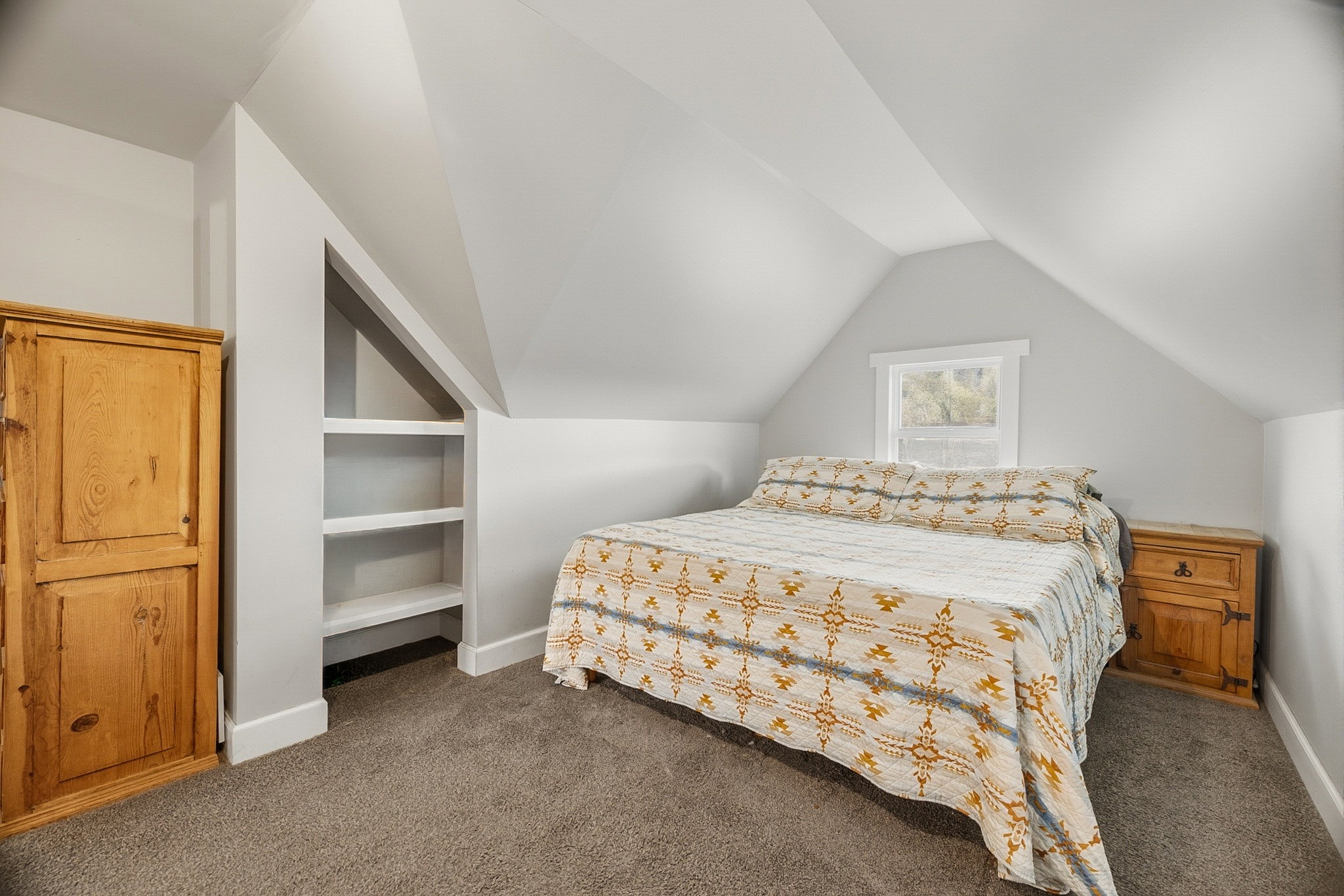 Carpeted room featuring a white-trimmed window, built-in shelving, vaulted ceilings, and light gray wall finishes