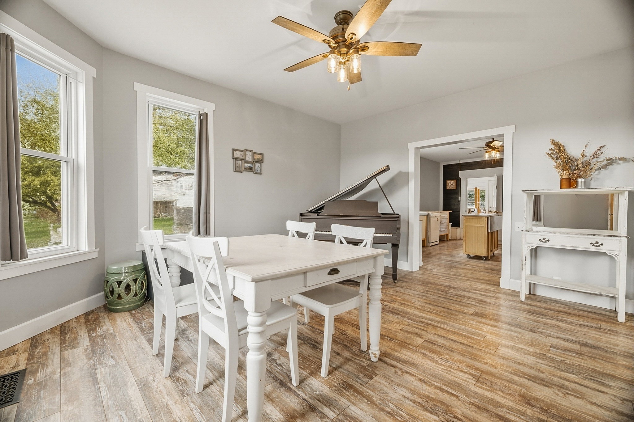 Spacious room with wood-finish flooring, two large windows, and a ceiling fan with integrated lighting