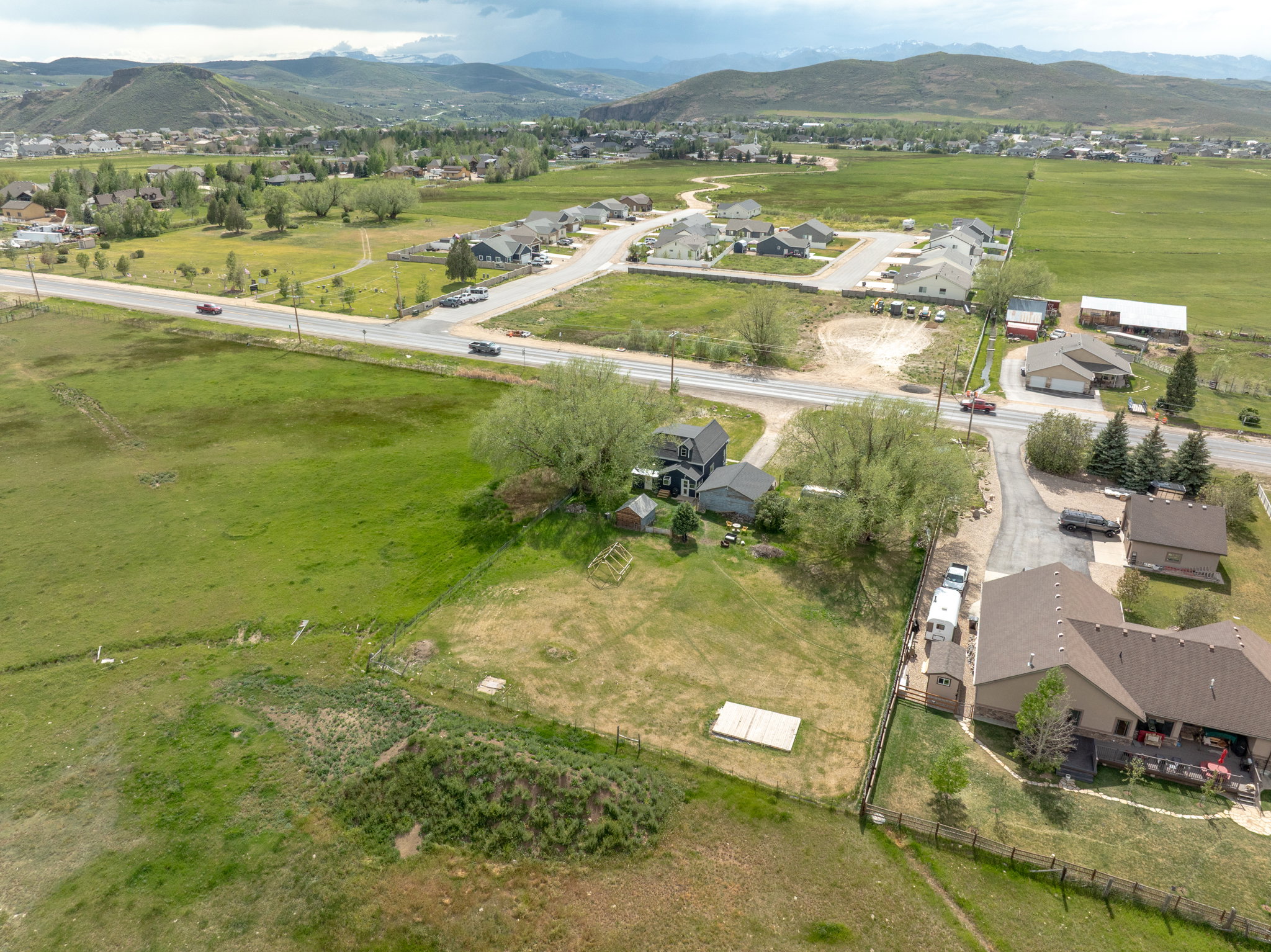 Expansive property featuring a gravel driveway, multiple outbuildings, and mature trees