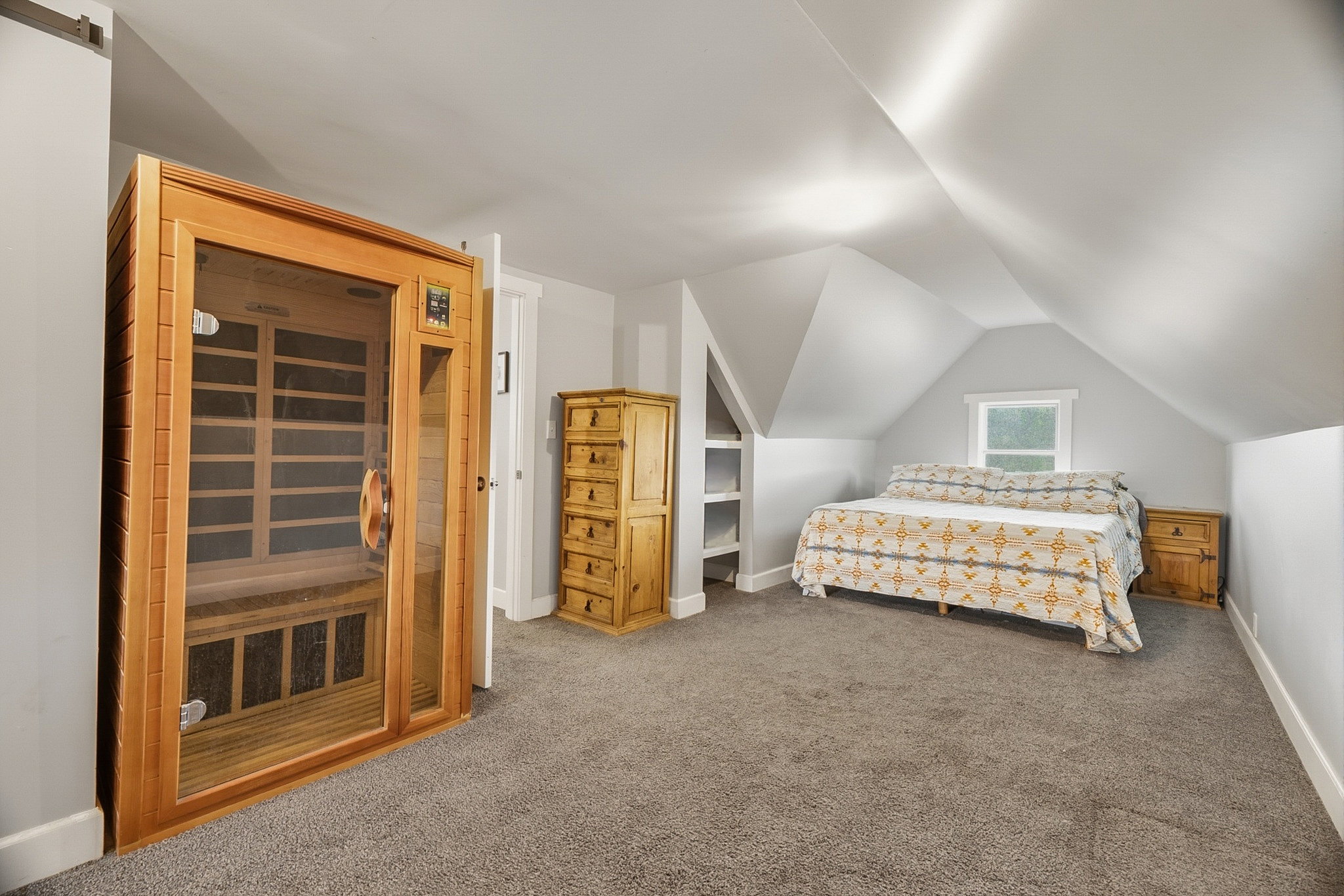 Wood-paneled sauna with glass door, recessed shelving, window, soft gray walls, and gray carpeted flooring