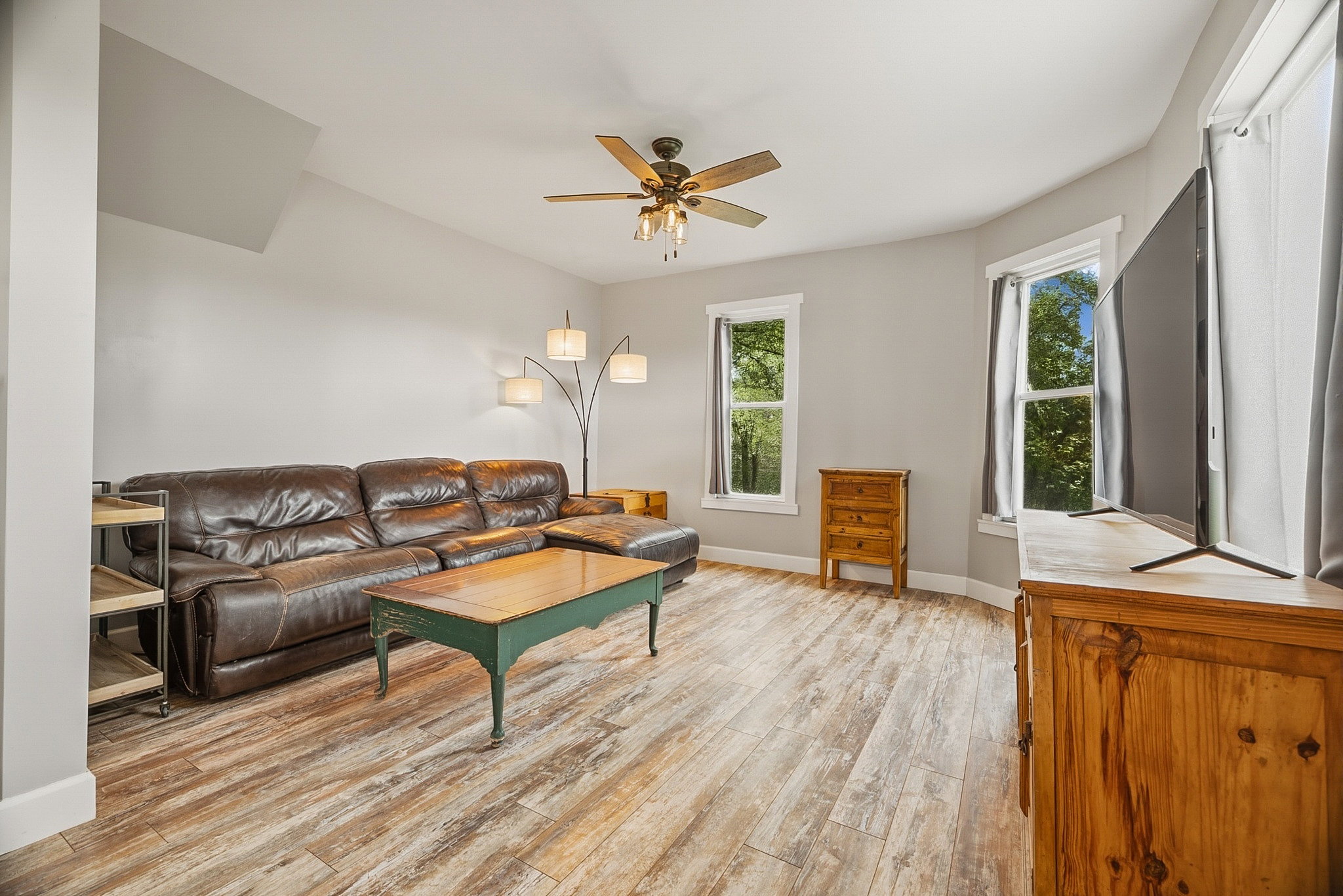 Spacious room featuring wood-finish flooring, light gray walls, and multiple windows