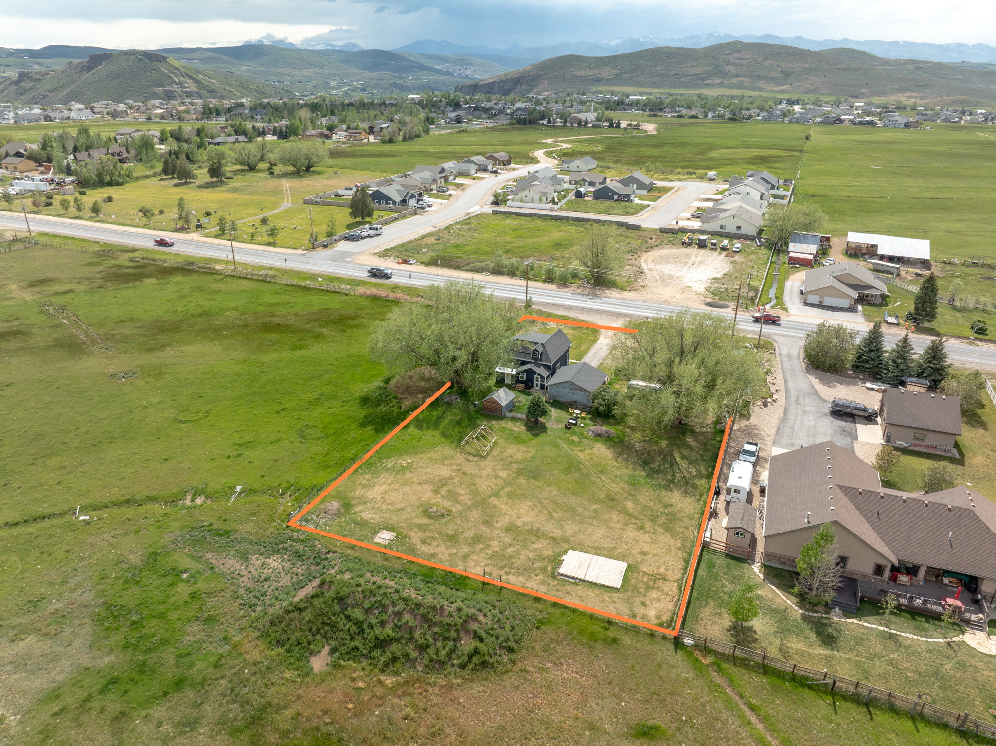 Expansive lot featuring a large grassy area, mature trees, and mountainous terrain in the background
