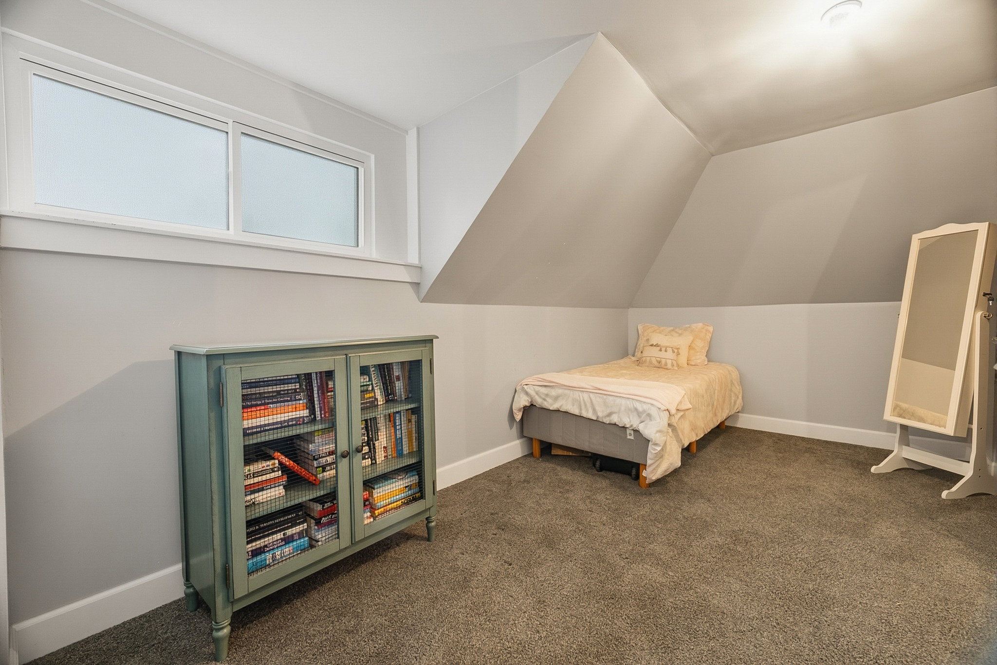 Attic room featuring a sloped ceiling, light gray wall paint, and gray carpet flooring