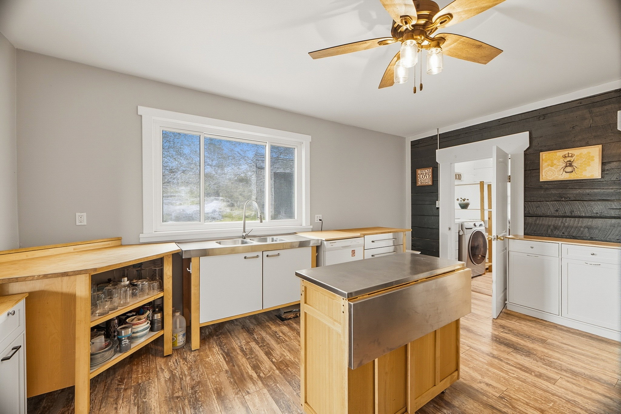 Kitchen featuring wood-finish flooring, white cabinetry, a double basin stainless steel sink, wood countertops, and a ceiling fan with light fixture