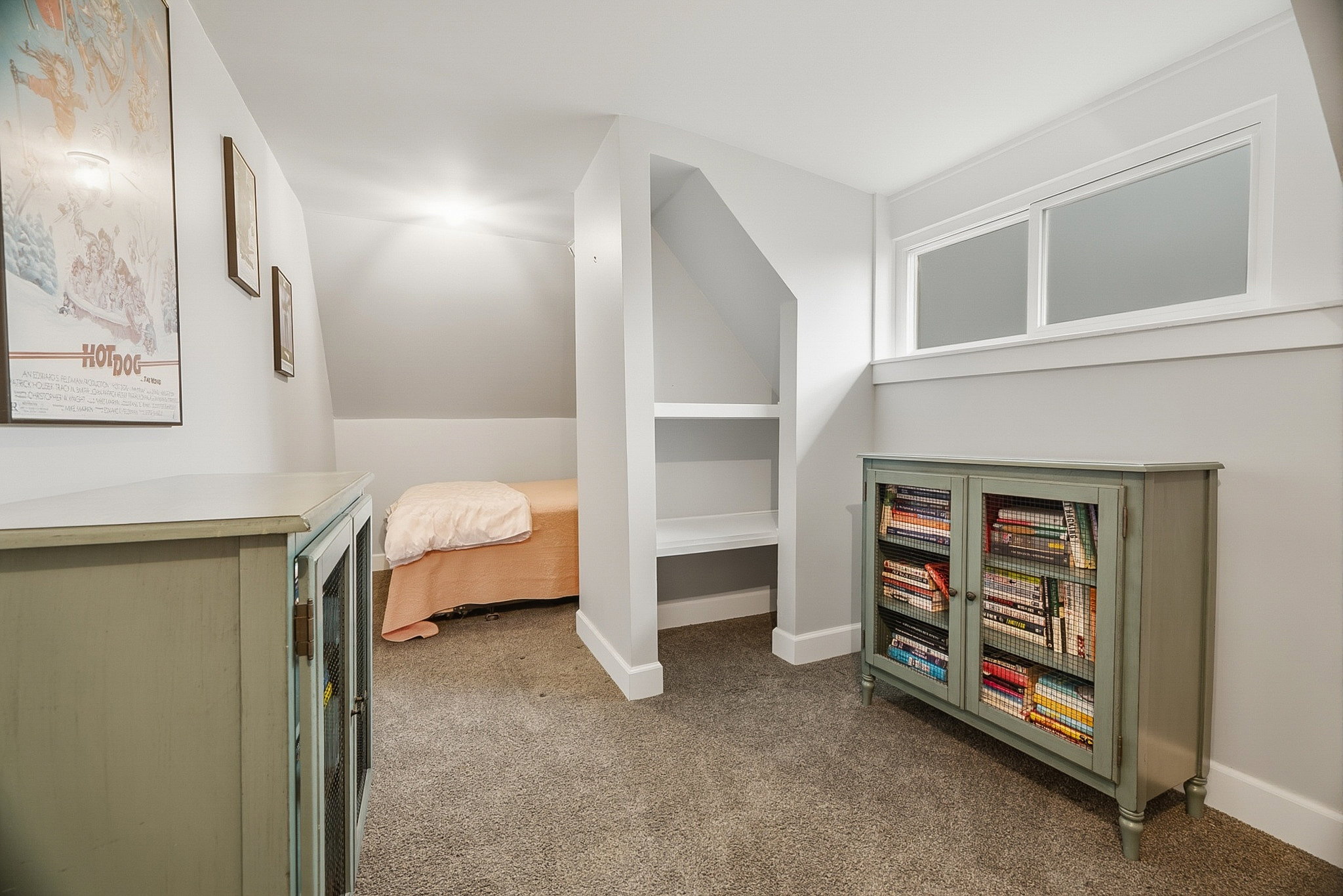 Carpeted room featuring a built-in shelving unit, a window with white trim, and light gray wall paint