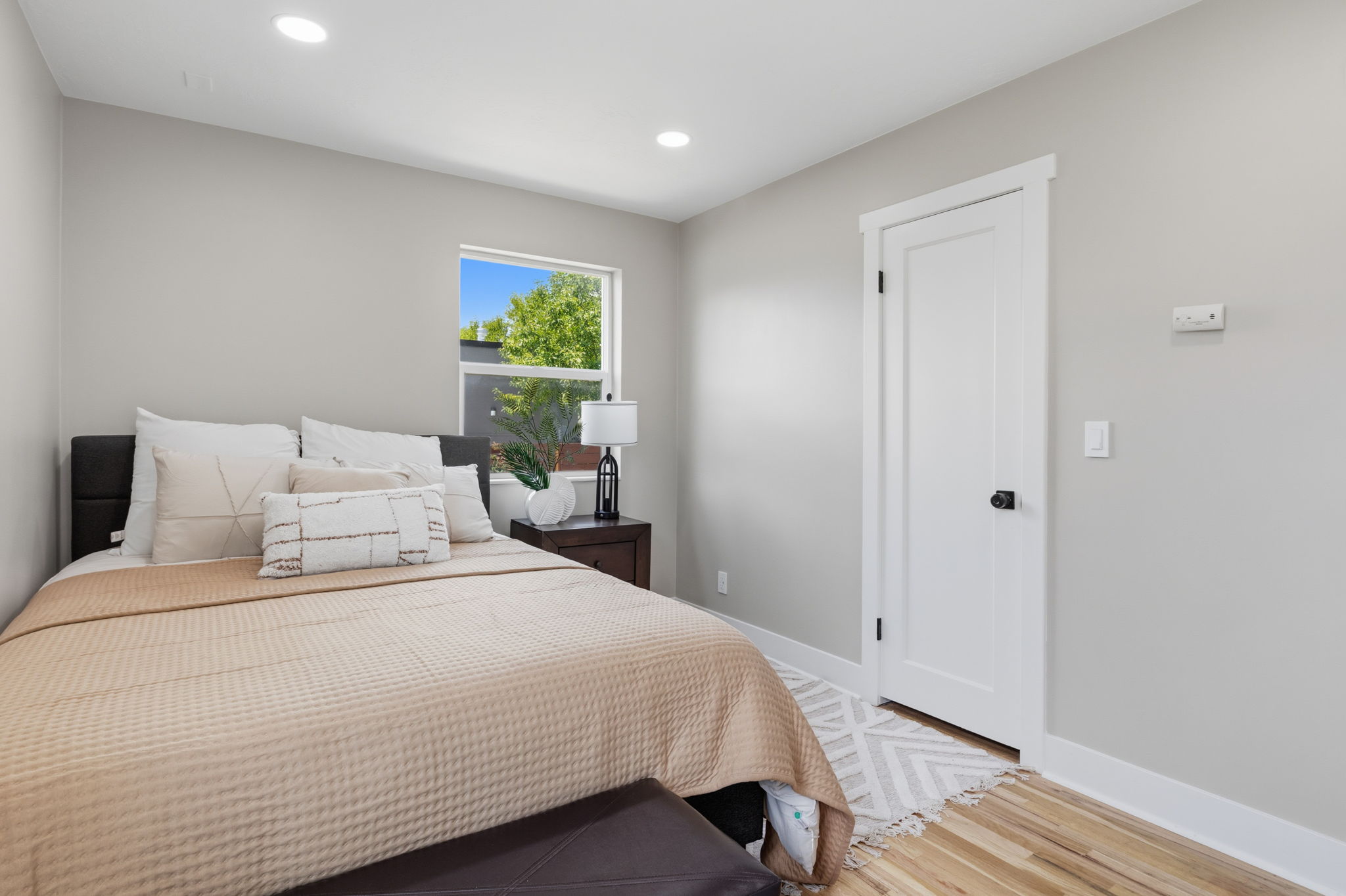 Recessed ceiling lighting illuminates light gray walls and wood-finish flooring