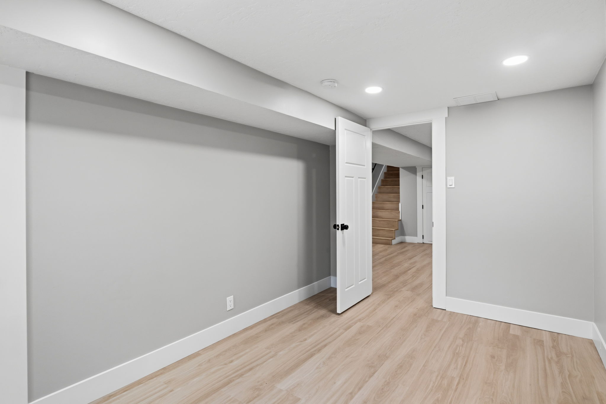 Room featuring light gray walls, white trim, and wood-finish flooring