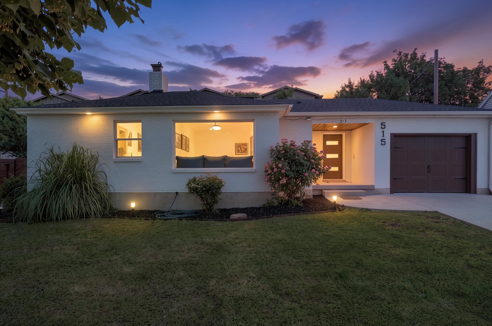 Contemporary exterior featuring a white brick façade, dark wood-grain garage door, and a modern entry door with frosted glass inserts