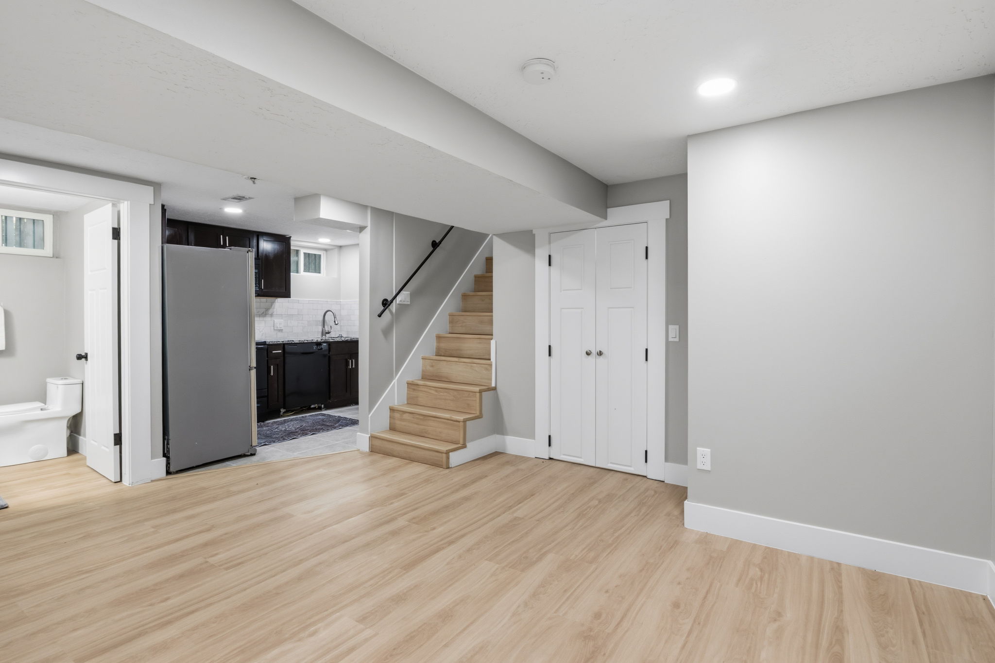 Open-concept lower level featuring wood-finish flooring, recessed lighting, and light grey wall finishes